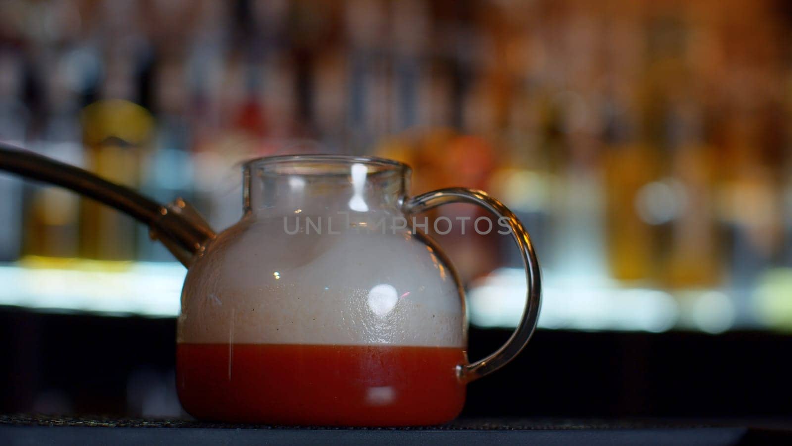 Close up of making red fruit tea at a bar or restaurant. Media. Bartender adding smoke into the tea pot through the tube