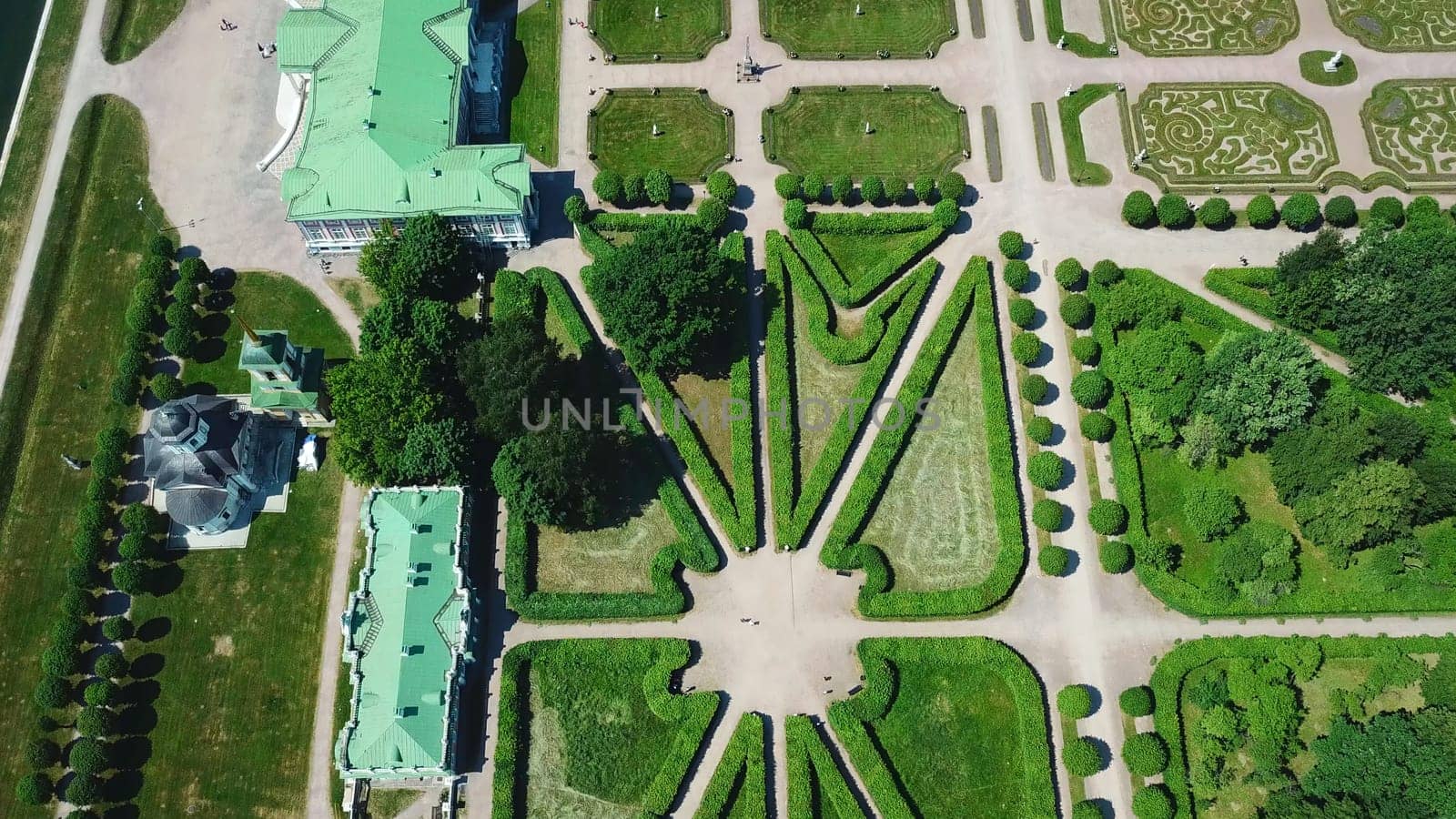 Top view of royal garden with patterns and ancient buildings. Creative. Amazing beauty of garden pattern and trails of royal palace. Territory of old rich estate with garden on sunny summer day.