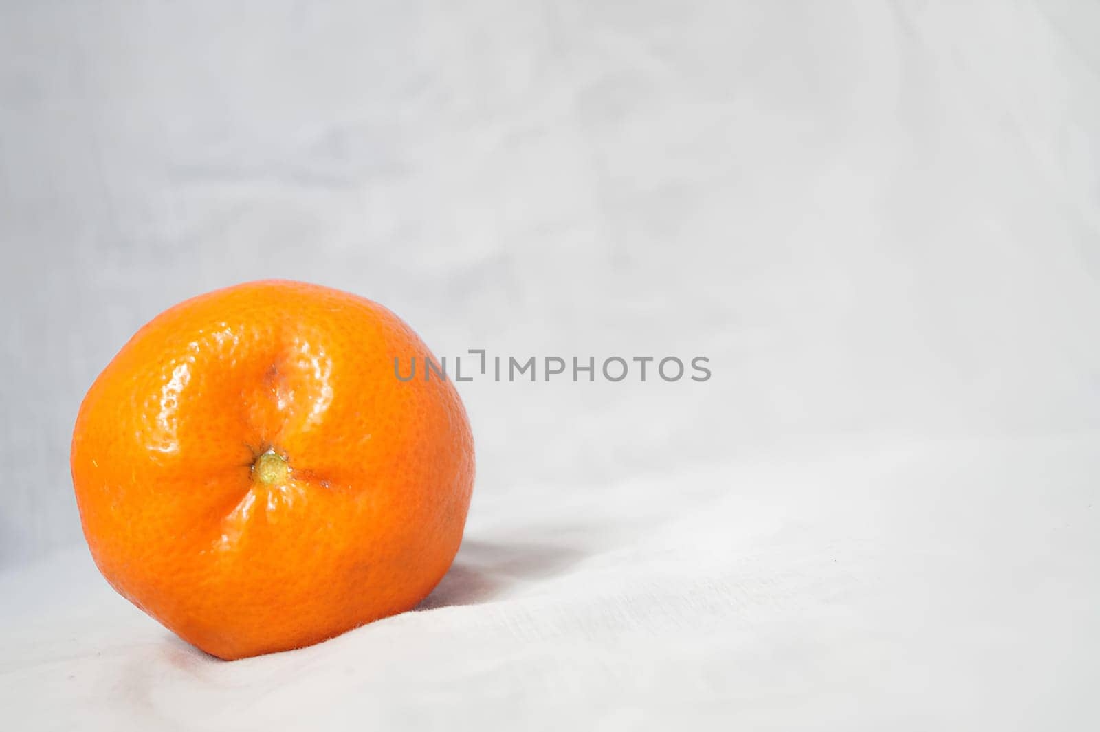 A small orange sits on a white background. High quality photo