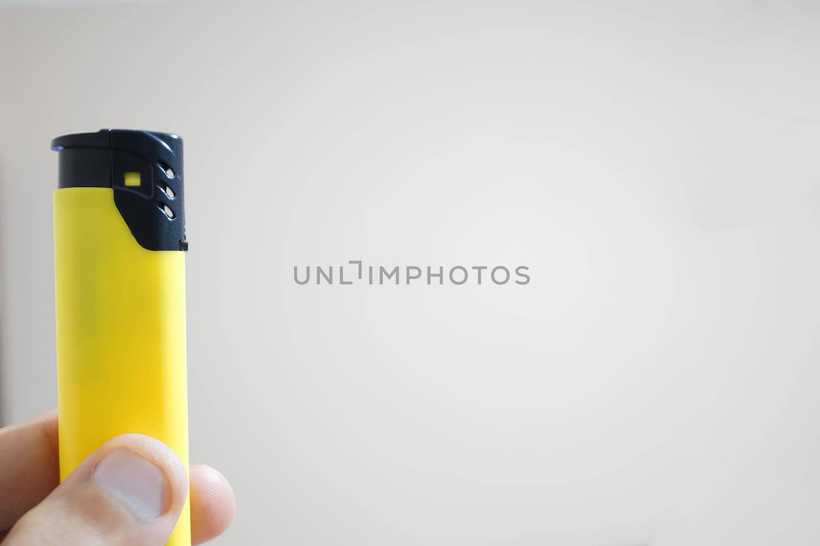 A person is holding a yellow lighter. High quality photo