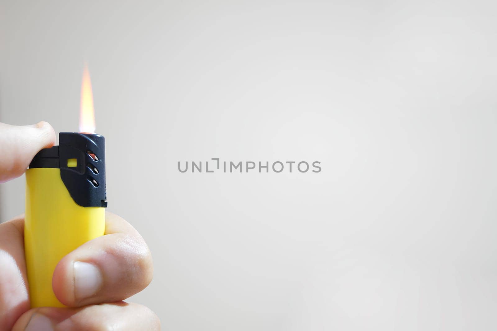 A person is holding a lighter with a yellow and black handle. High quality photo