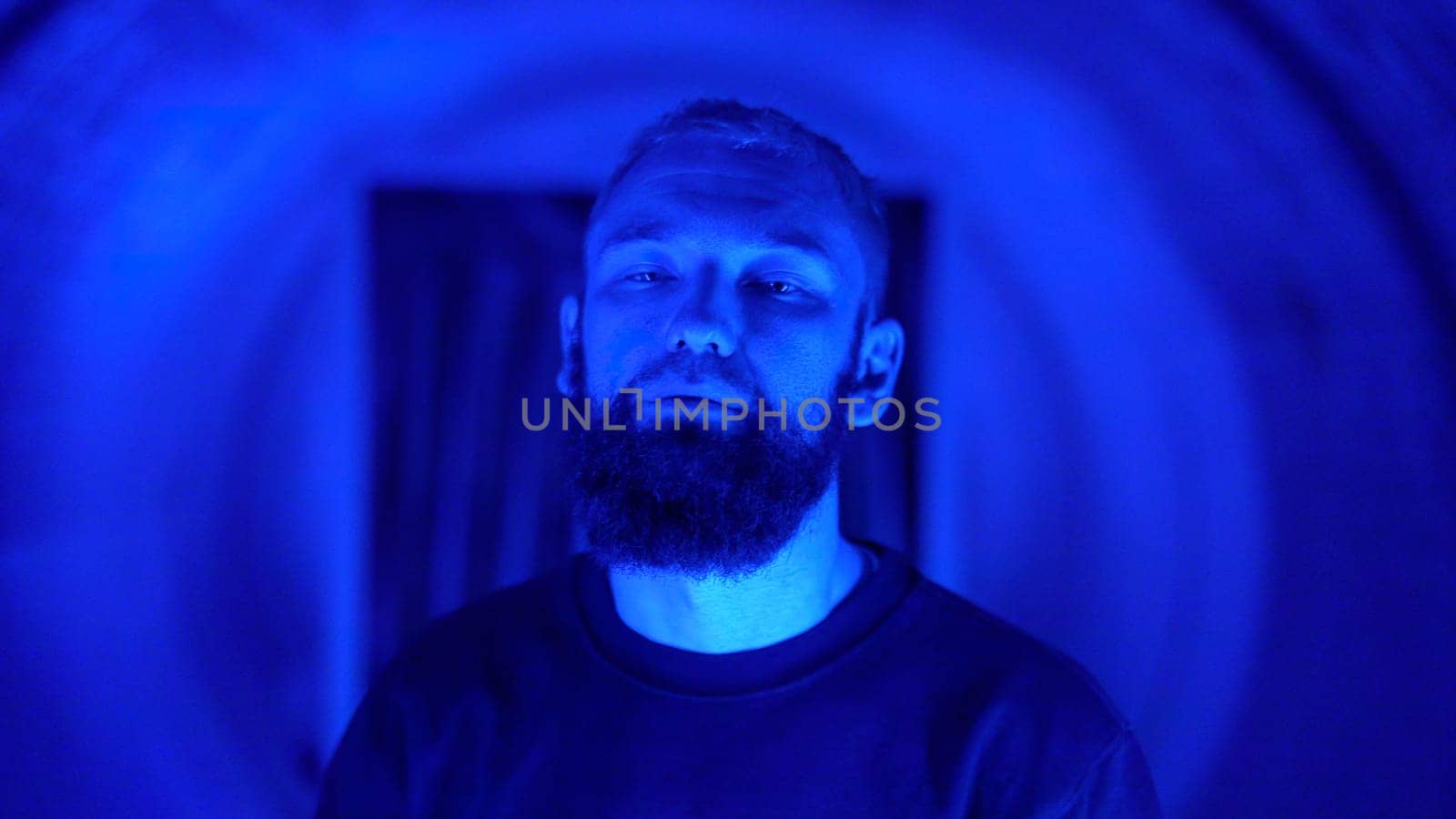 Portrait of a young stylish hipster man rapper moving and posing to the camera. Media. Neon lighting background creating effect of spinning tunnel. by Mediawhalestock