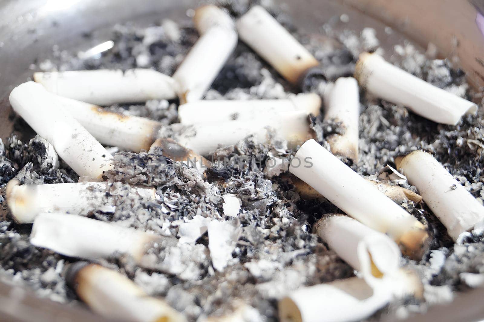 A pile of burnt cigarette butts in a pan. High quality photo