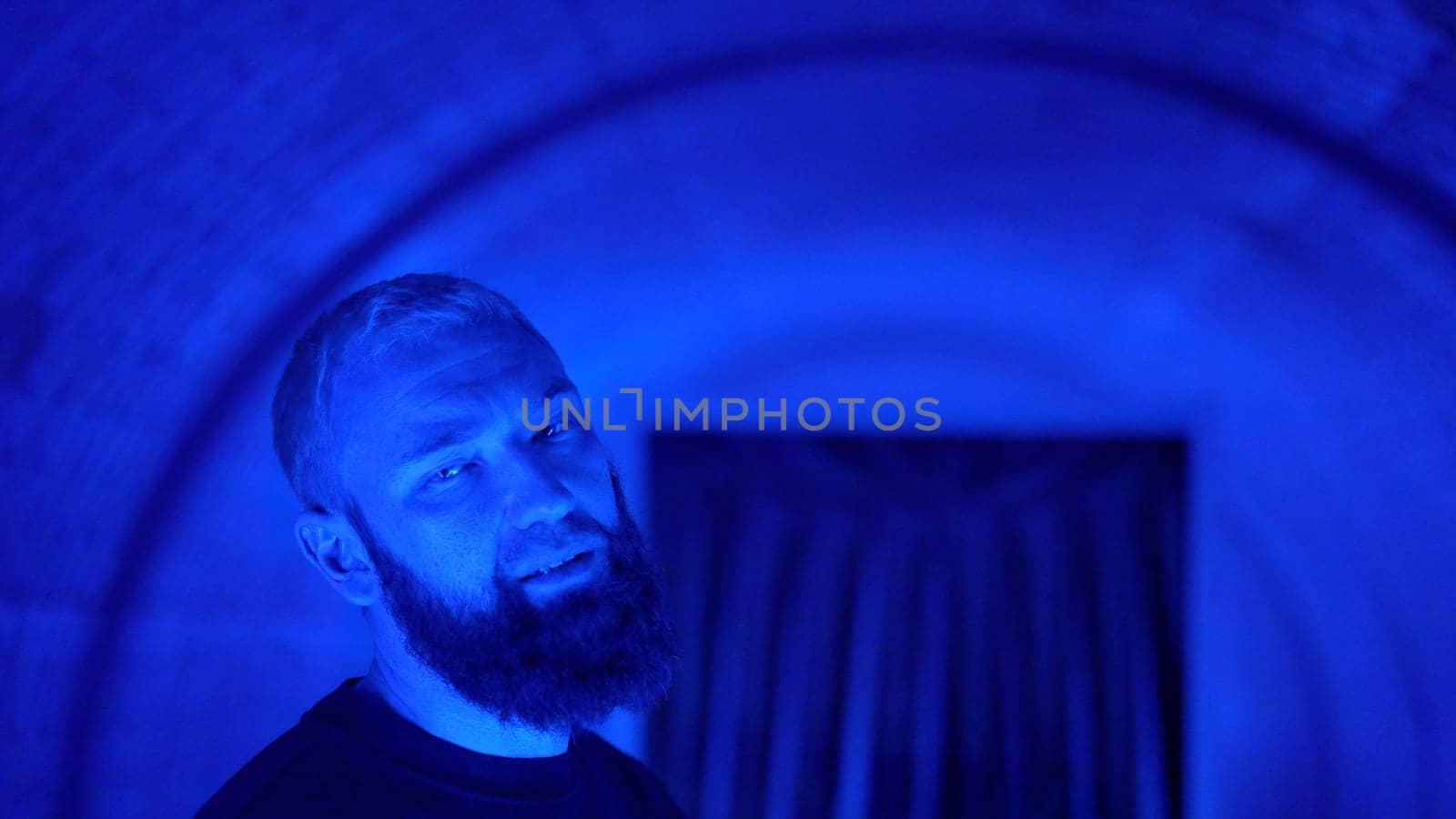 Portrait of a young stylish hipster man rapper moving and posing to the camera. Media. Neon lighting background creating effect of spinning tunnel