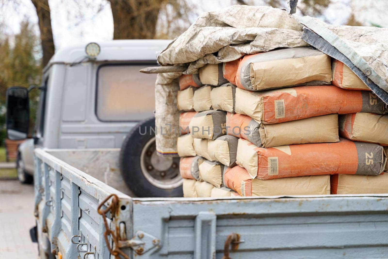 A pickup truck bed is filled with stacked cement bags, indicating ongoing construction work at a site.