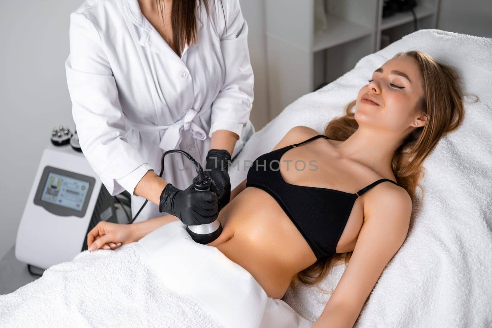 Young woman getting ultrasound cavitation body contouring treatment and anti cellulite therapy. Hardware cosmetology for body sculpting.
