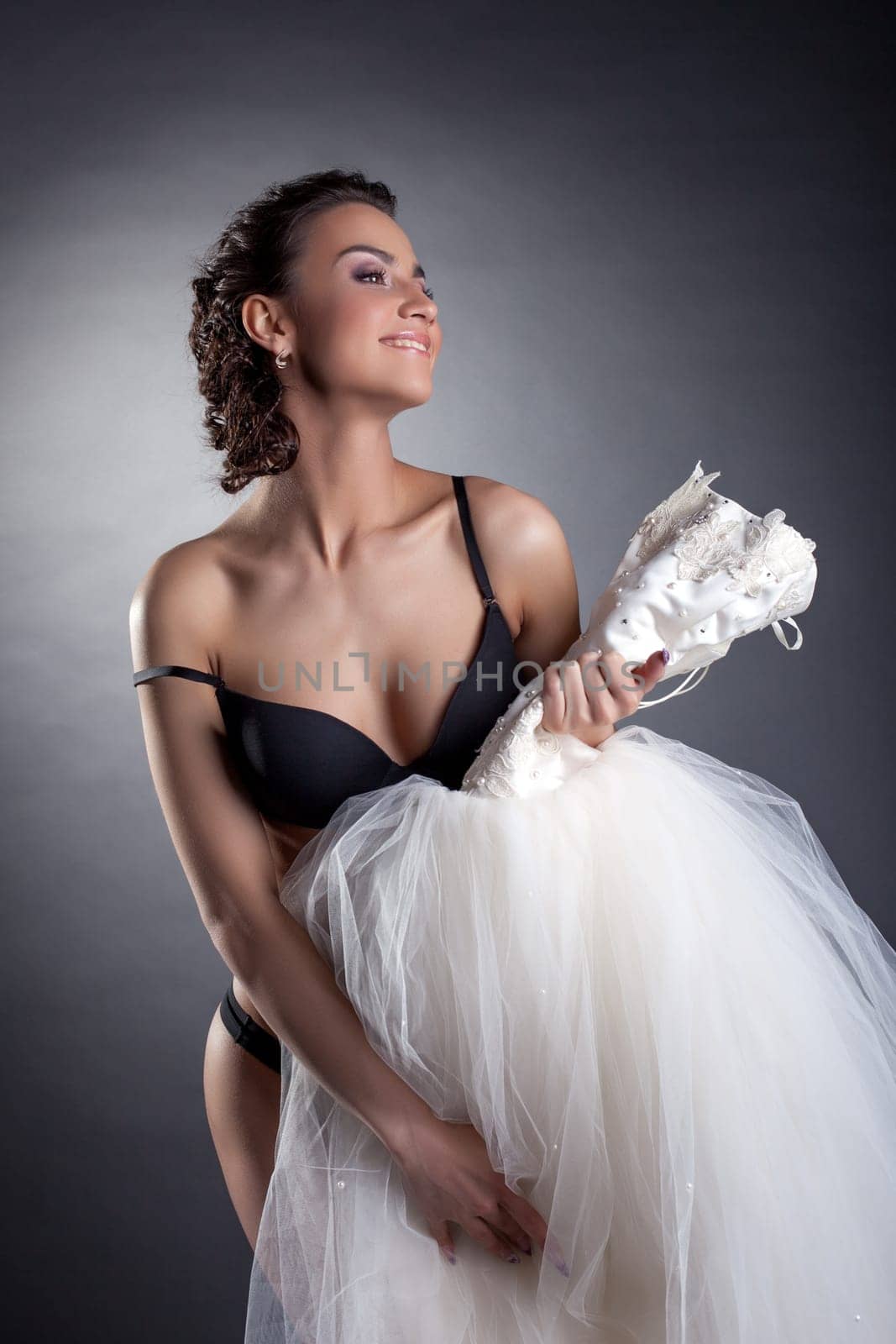 Portrait of cheerful bride posing naked in studio, on gray background