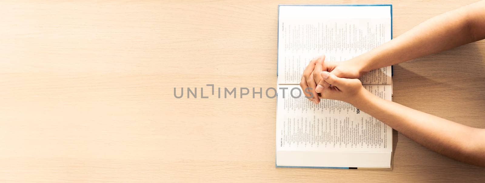 Female prayer folding hand on holy bible book on wooden church table. Concept of hope, religion, faith, christianity praying for love and god blessing. Warm and brown background.Top view. Burgeoning.