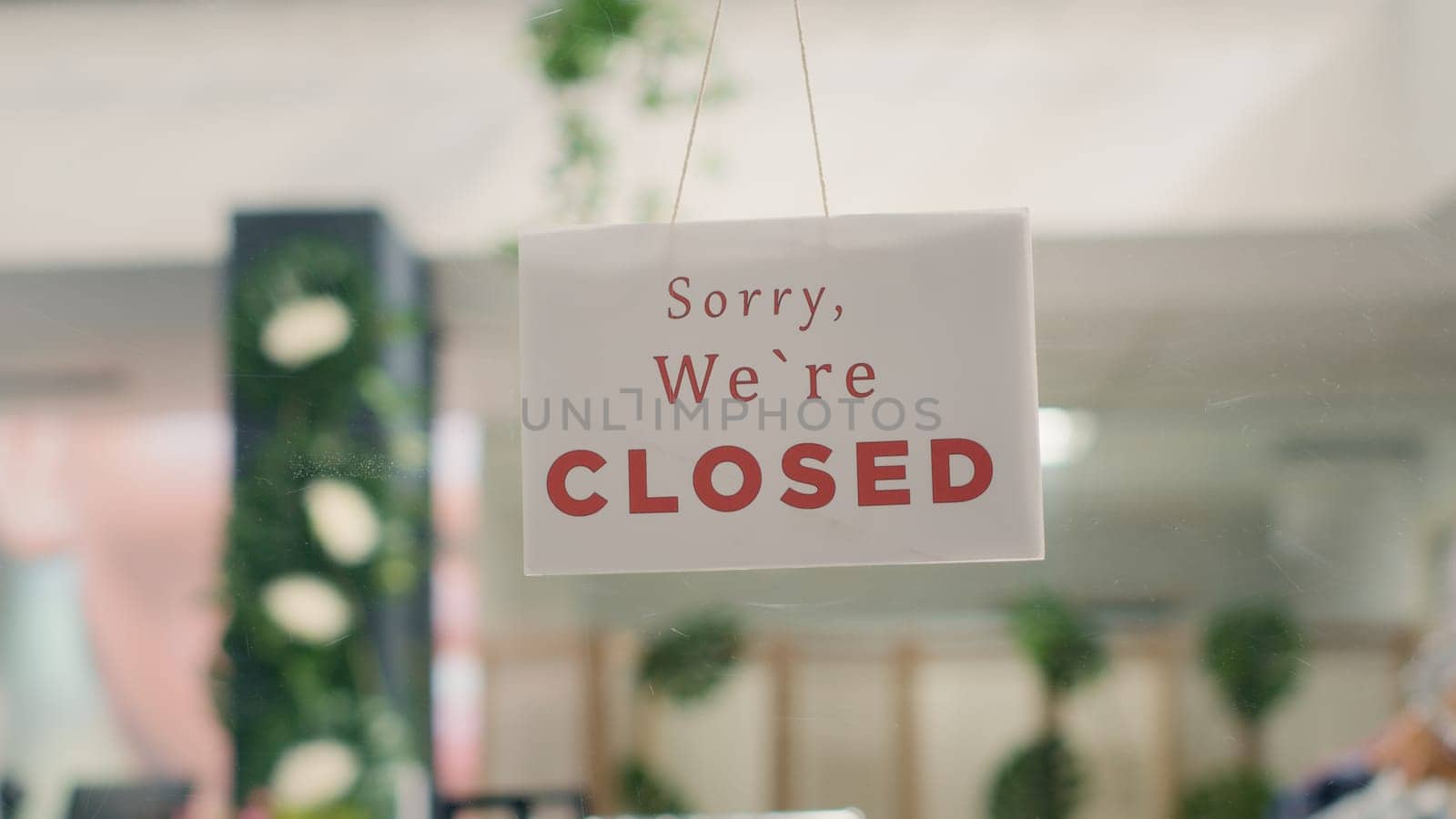 Sorry we are closed sign in empty fancy fashion boutique with stylish formal clothes. Message on designer clothing men premium showroom door announcing customers that shop is closed