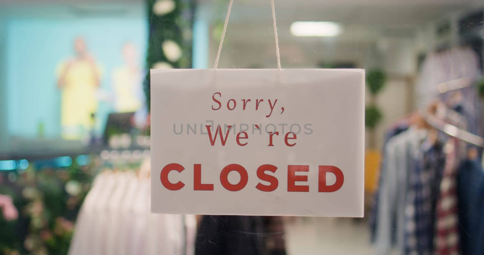 Extreme close up shot of close sign in expensive clothing store with elegant assortment of trendy clothes. Zoom in on sorry we are closed message on premium fashion boutique door with attire garments