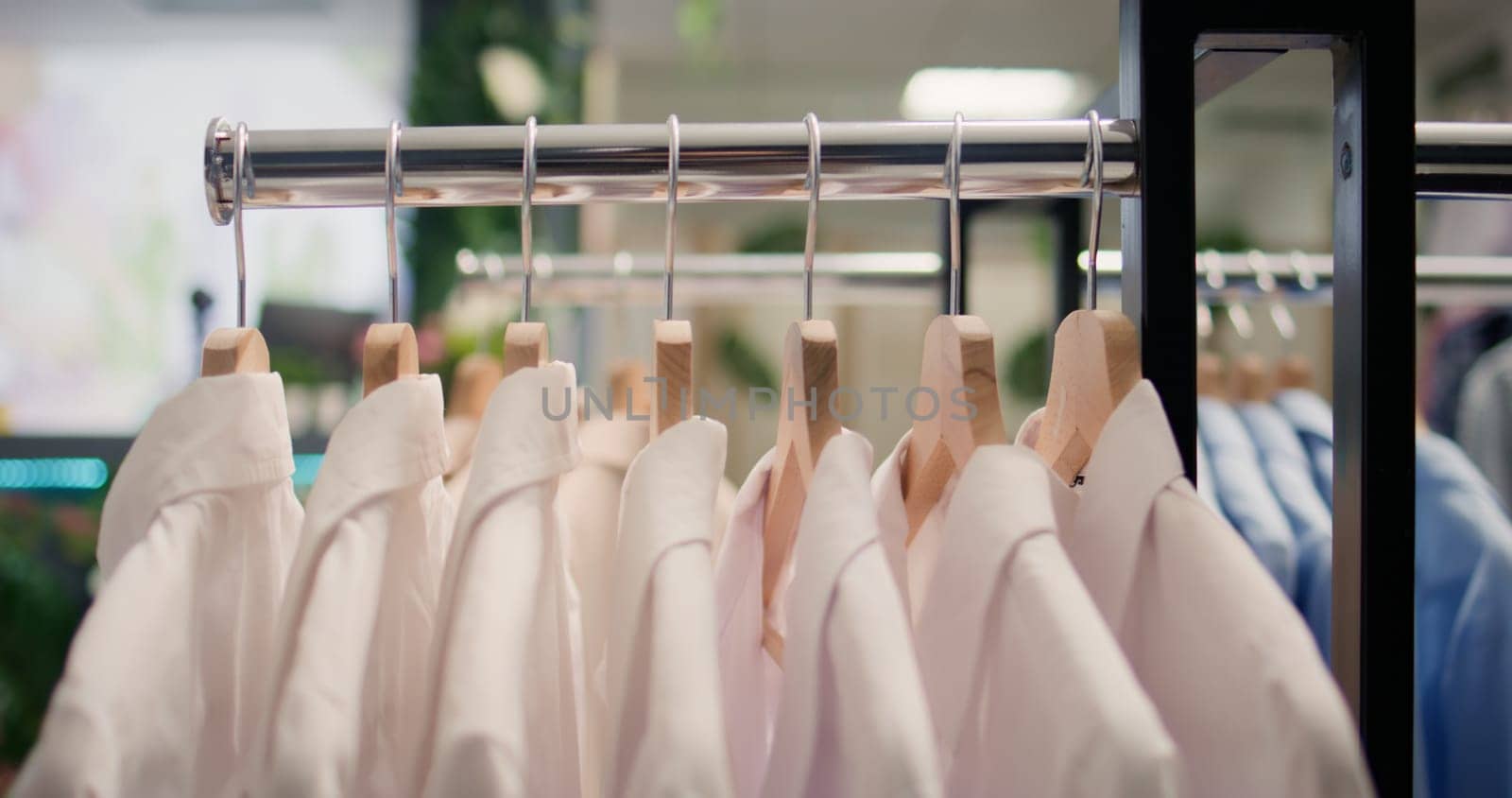 Close up shot of high quality garments in premium clothing store. Elegant formalwear white shirts in empty newly opened luxurious fashion boutique awaiting customers, jib down shot