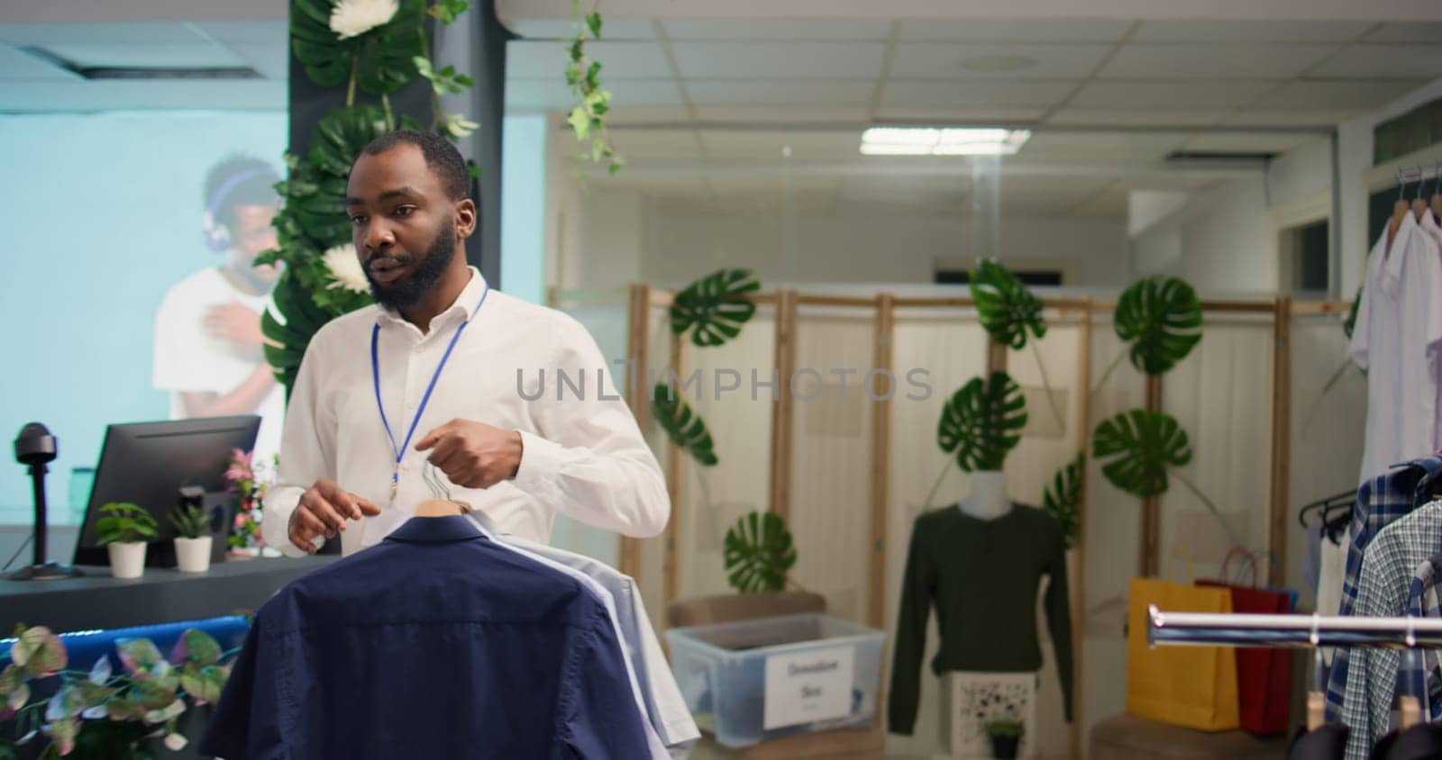 Tracking shot of employee working in SH clothing shop arriving with simple stylish shirts, placing them racks. Retail assistant preparing new collection of formal garments in discount fashion store