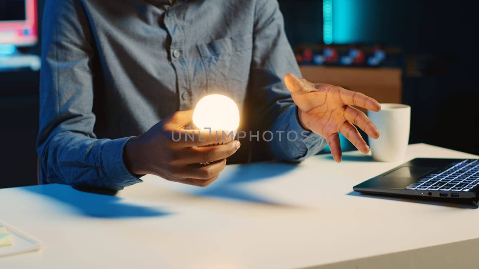 African american content creator in dimly lit living room uses camera to film light bulb review for online streaming platforms. Media star hosts internet show, unboxing smart home technology