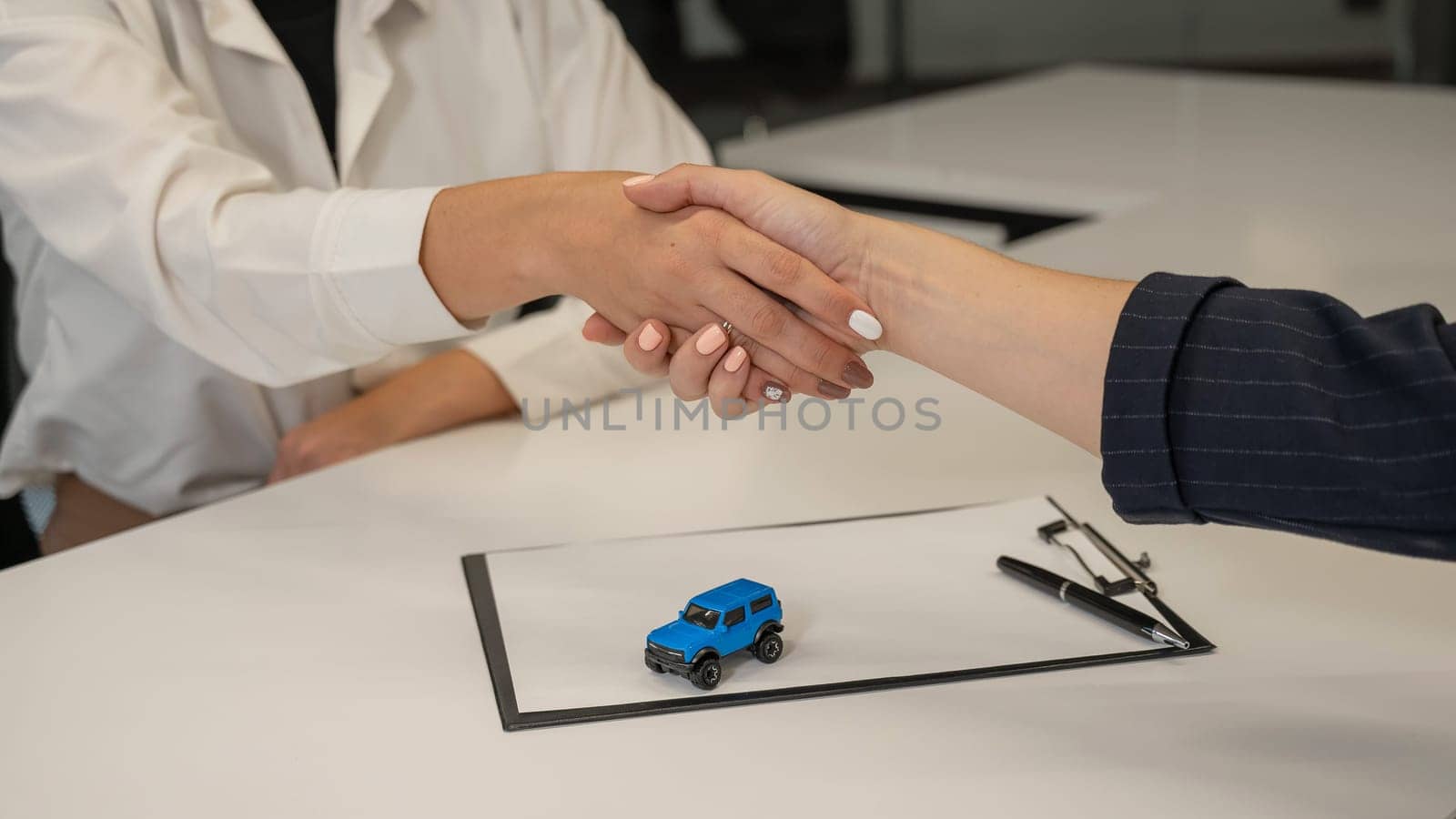 Car purchase deal. Seller and female buyer shaking hands. by mrwed54