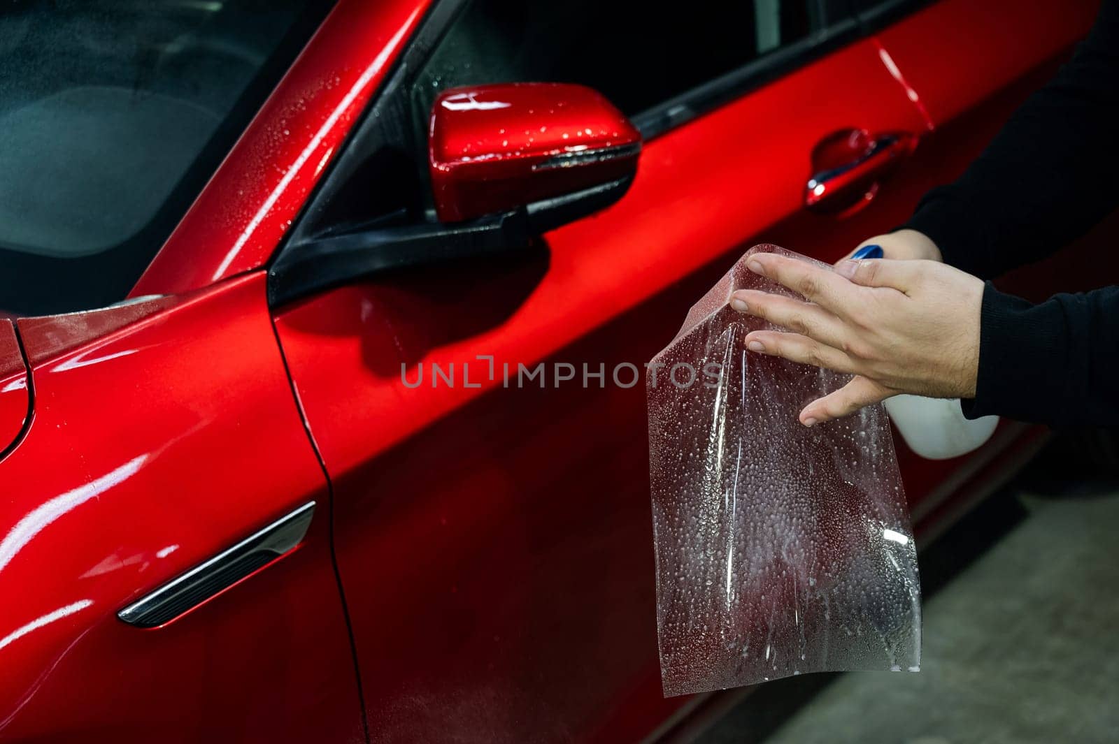 A technician sprays water before applying protective vinyl film to a car. by mrwed54