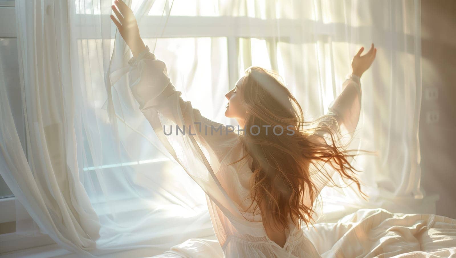 A woman with long hair is sitting on a bed with her arms outstretched in front of a window, showing a happy gesture. The wooden bed frame provides entertainment as she rests her hand on her thigh