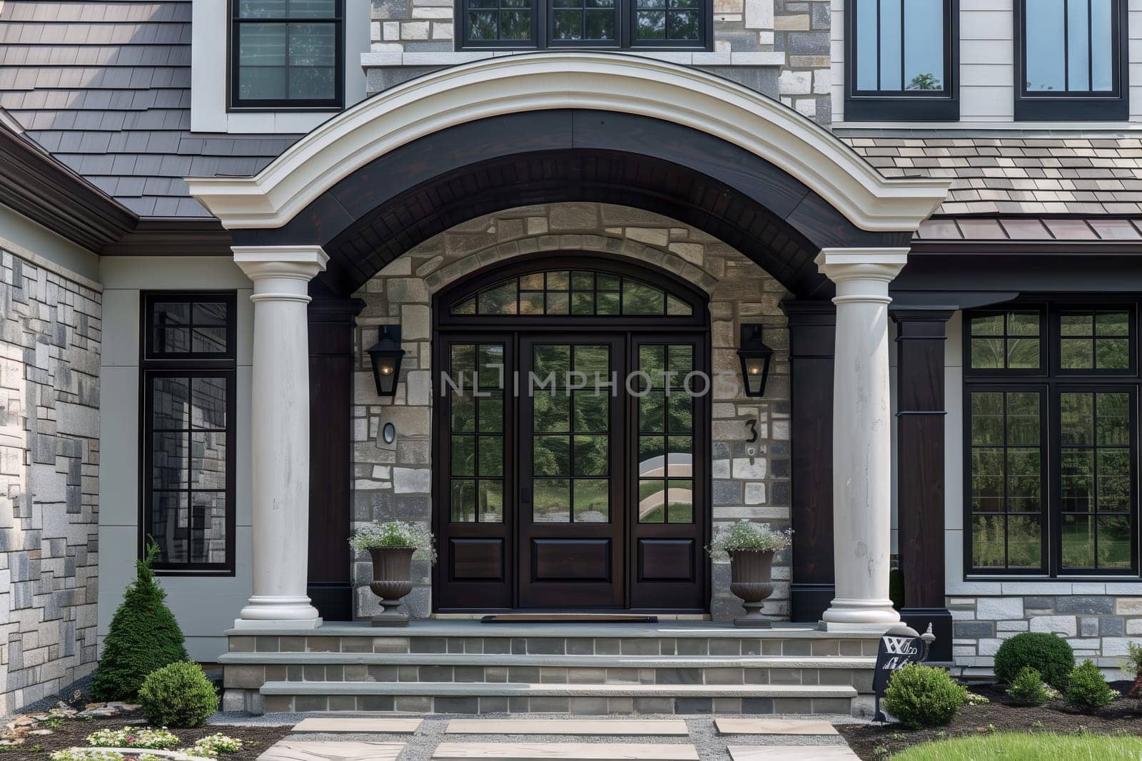 A spacious house with a grand porch, large door, and surrounded by lush grass. The brickwork adds charm to the building