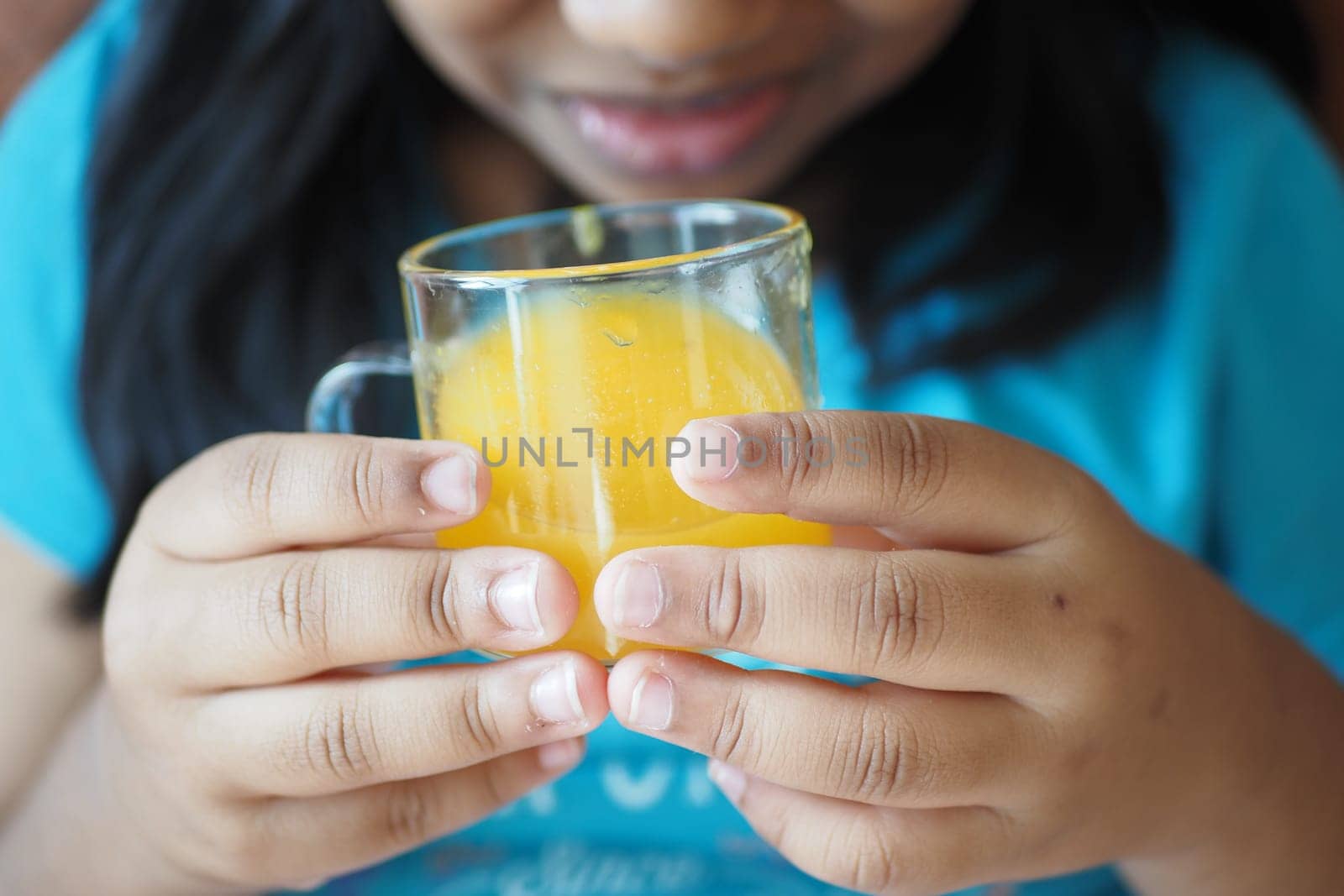 child hand holding a glass of orange juice .