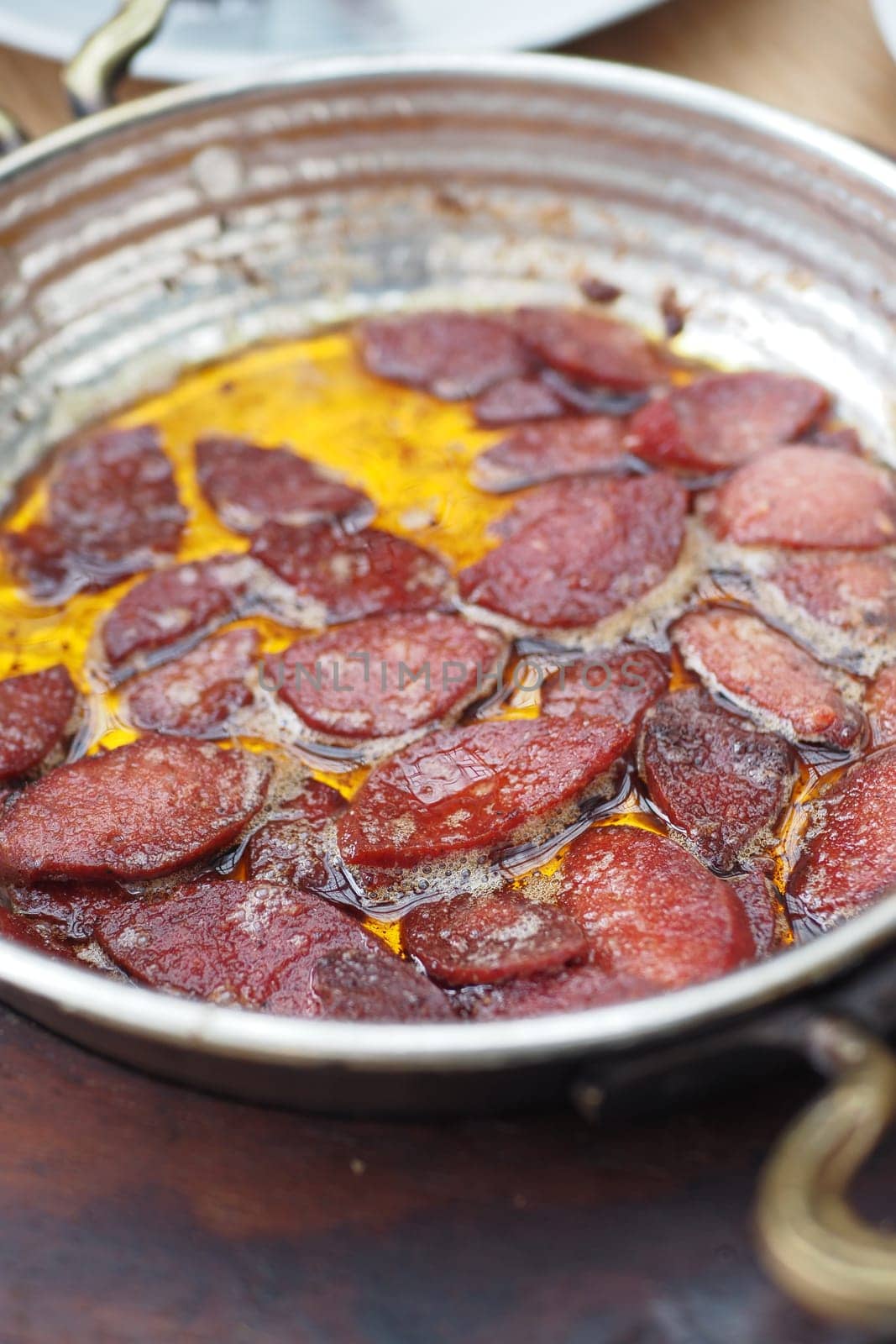 Cooking a dish of breakfast sausage in a pan on a wooden table,