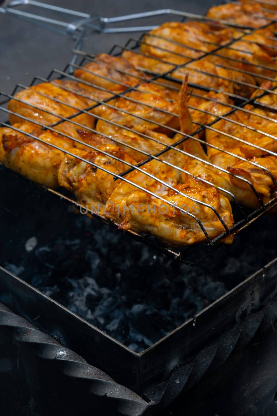 Delicious chicken frying on barbecue grill grate outdoor. Seasoning falling on fresh grilled chicken wings. Summer party food ideas. BBQ Juicy roasting chicken grill legs on grill grate