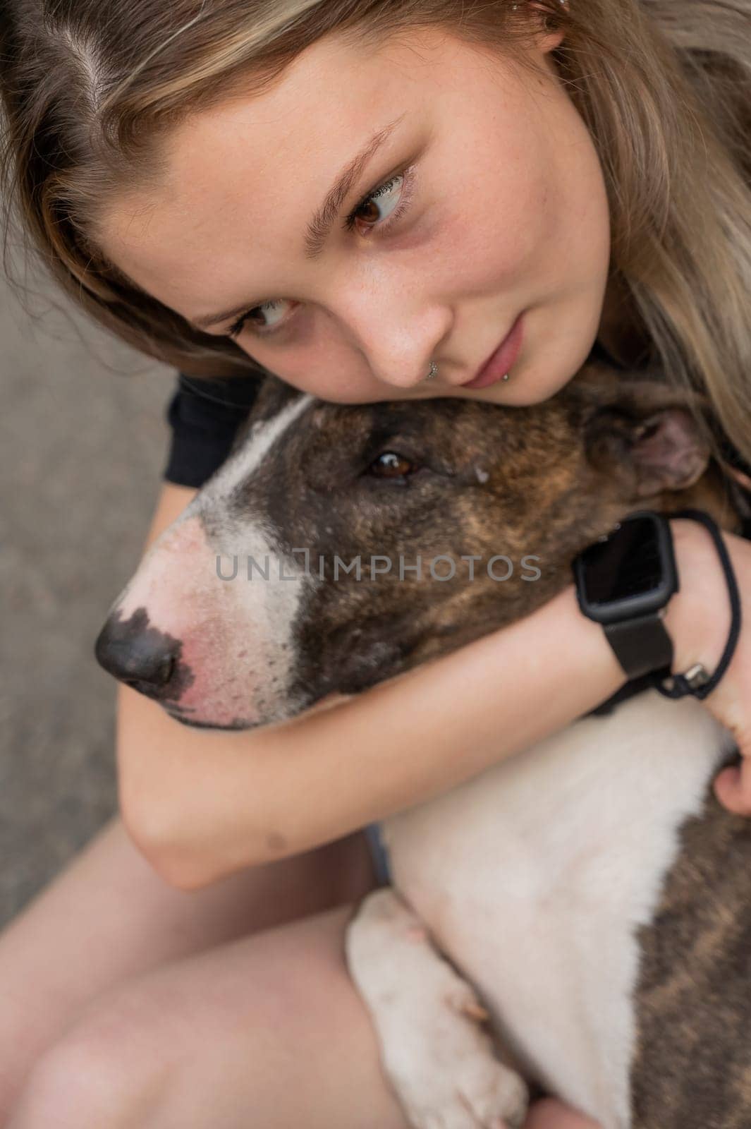 Portrait of caucasian woman hugging her bull terrier dog outdoors
