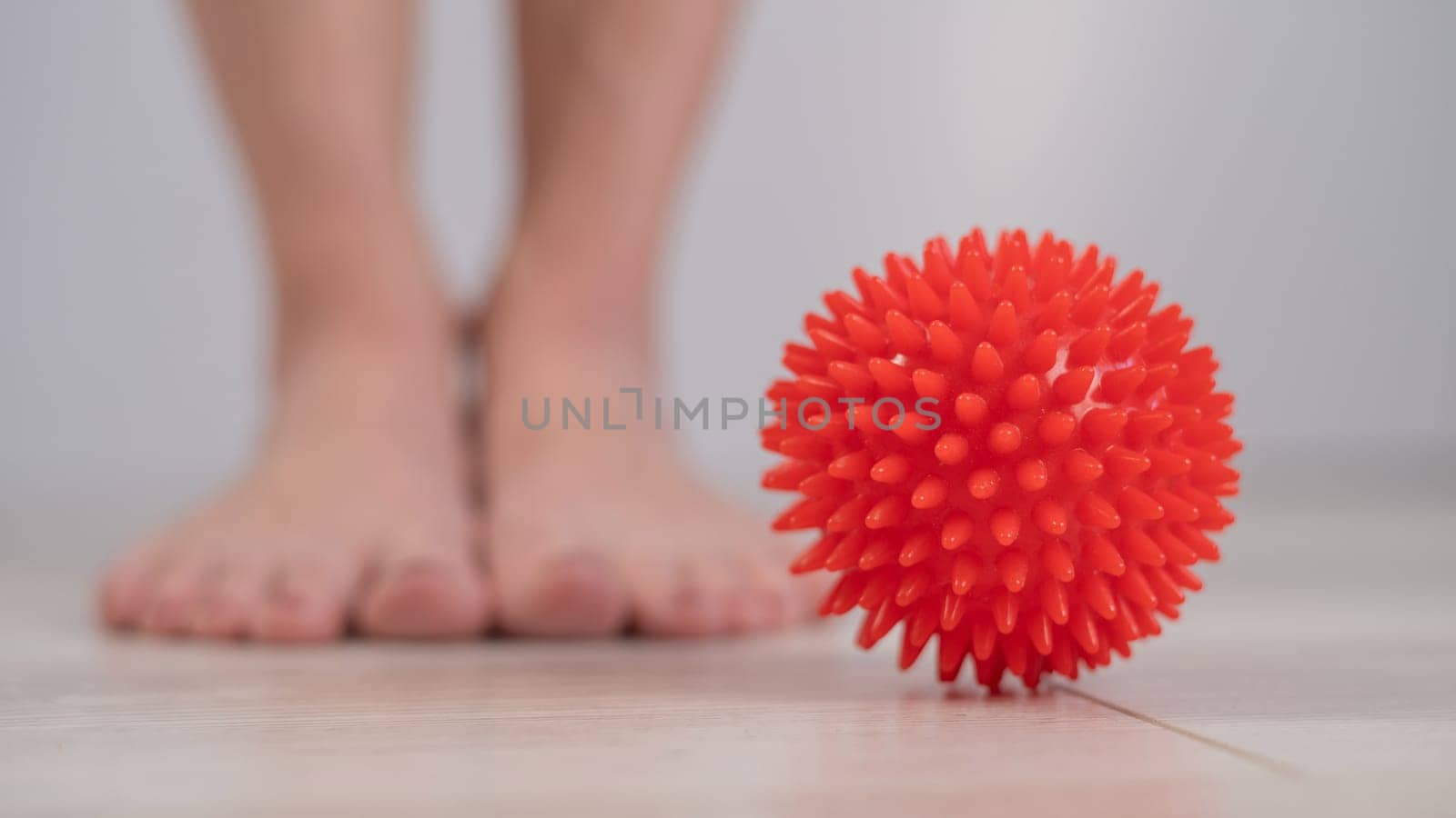 Close-up of a woman's foot on a massage ball with spikes