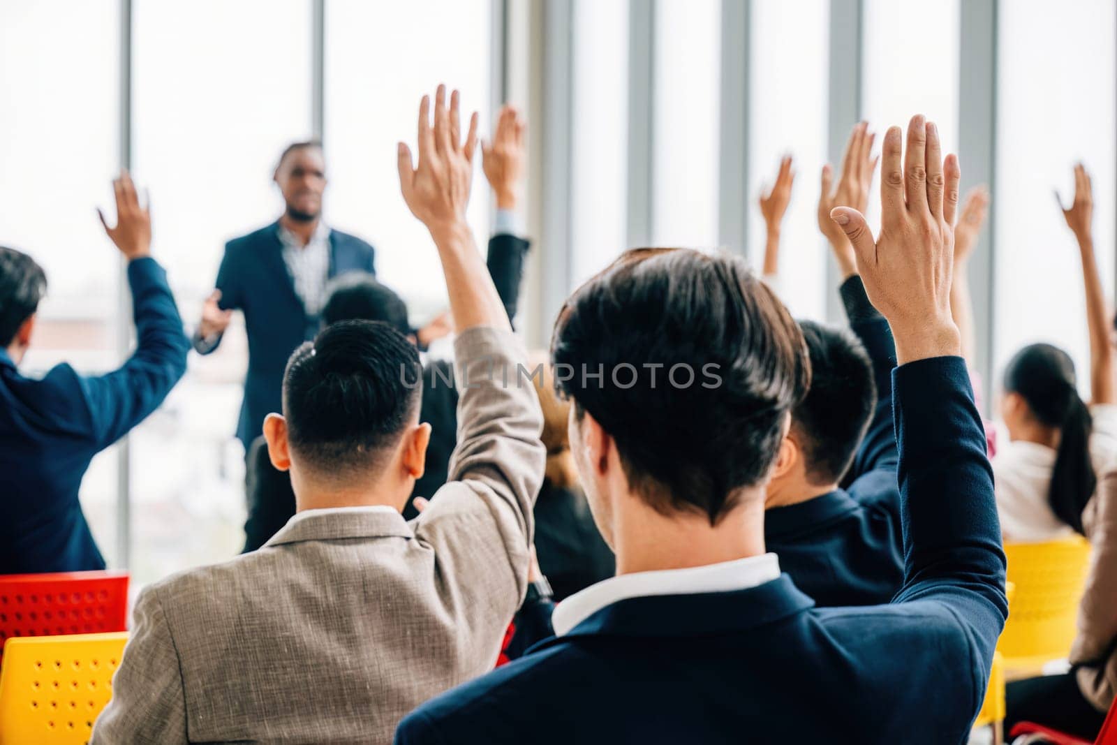 A meeting seminar and strategy session take place in the boardroom. Questions are posed and hands are raised demonstrating teamwork among colleagues and employees. by Sorapop