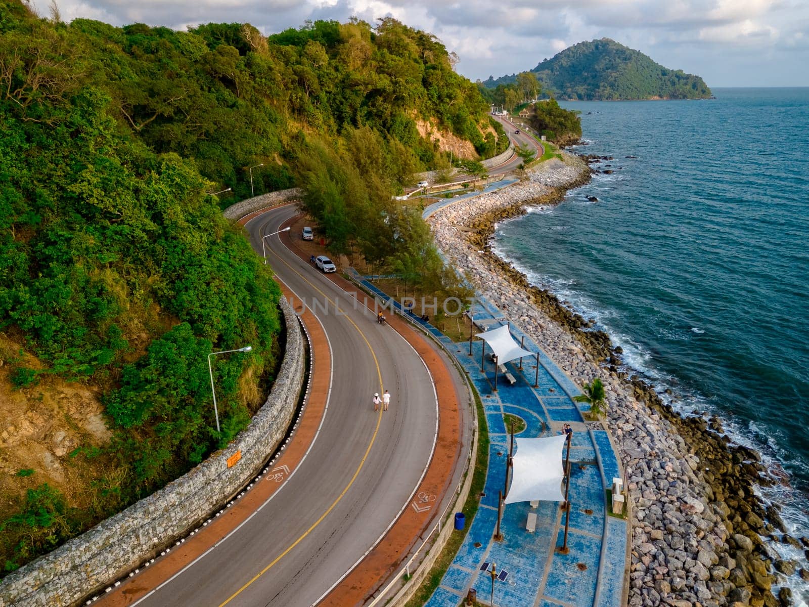 car driving on the curved road of Thailand. road landscape in summer. it's nice to drive on the beachside highway. Chantaburi Province Thailand, couple walking on the road at sunset