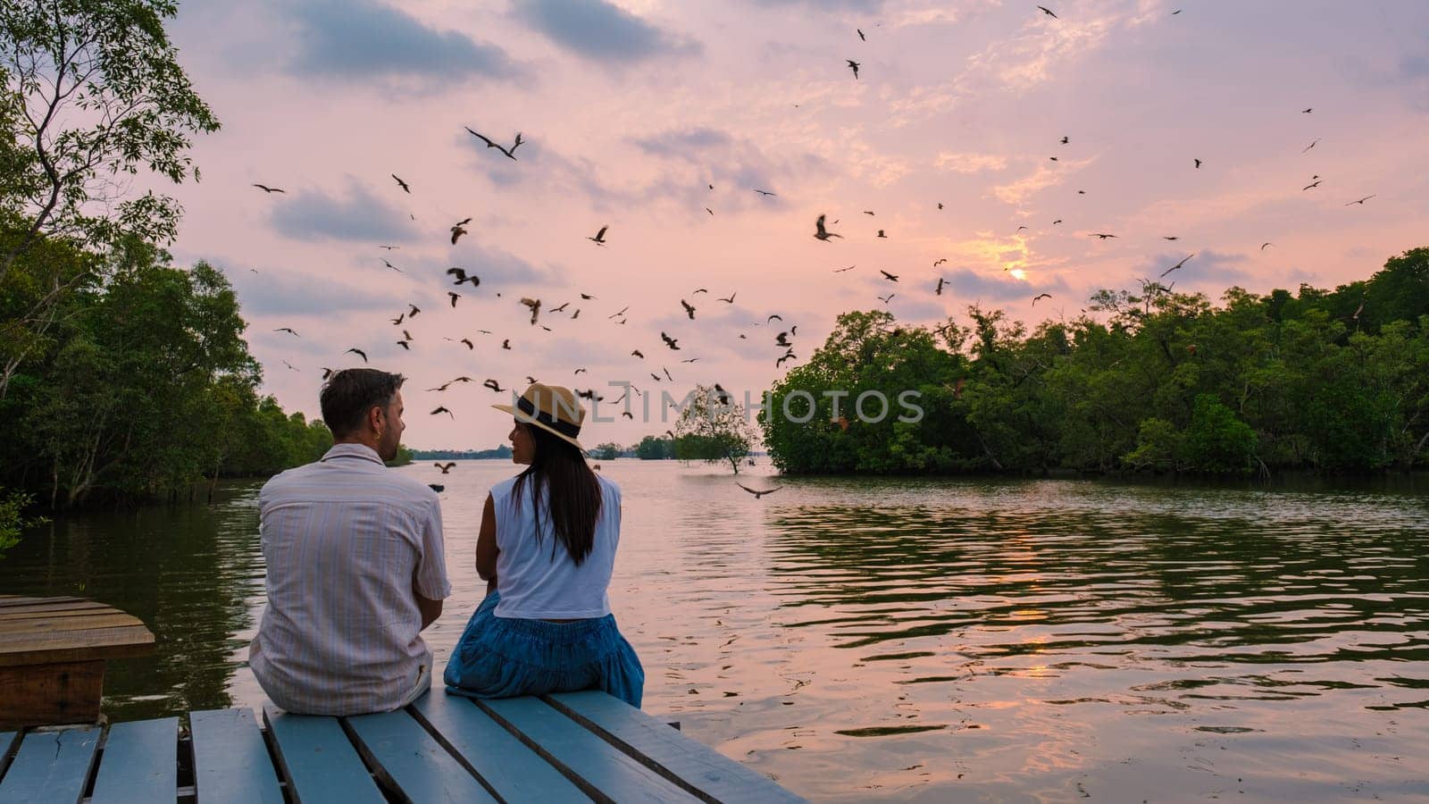 Sea Eagles at sunset in the mangrove of Chantaburi in Thailand, couple of men and women watching the sunset on a wooden pier