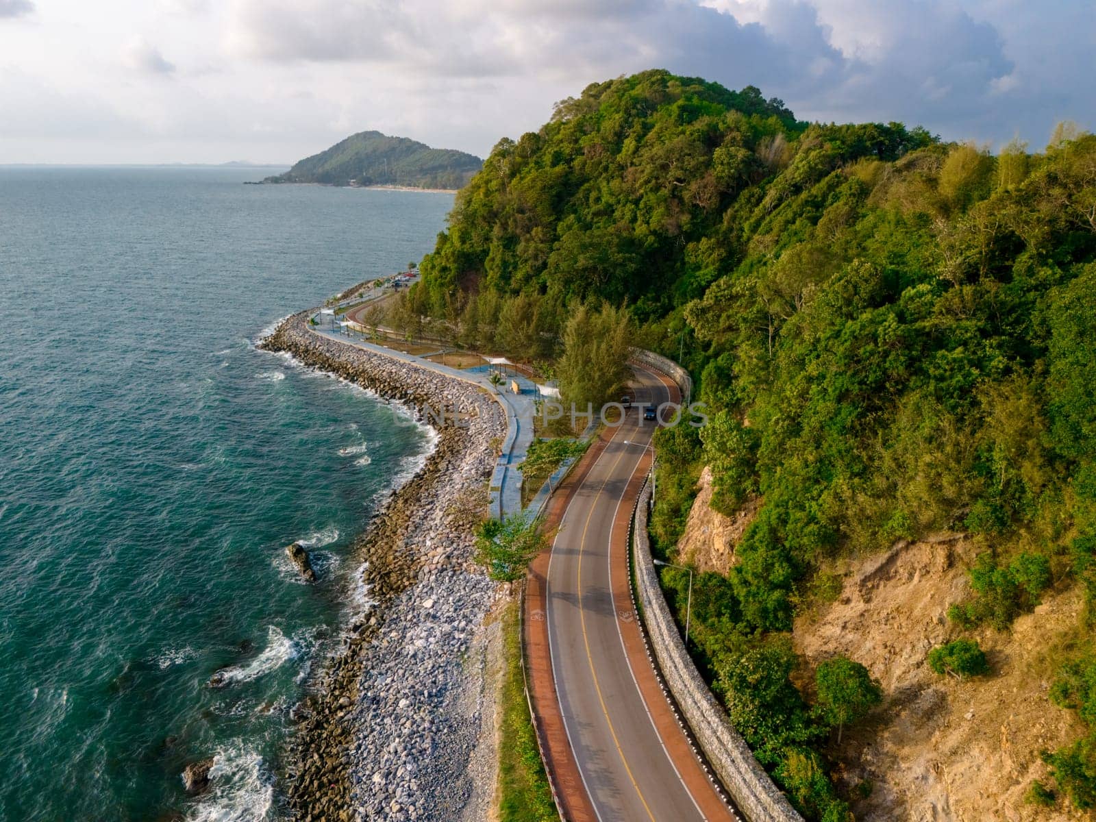 car driving on the curved road alongside the ocean beach road at sunset in summer. it's nice to drive on the beachside highway. Chantaburi Province Thailand,