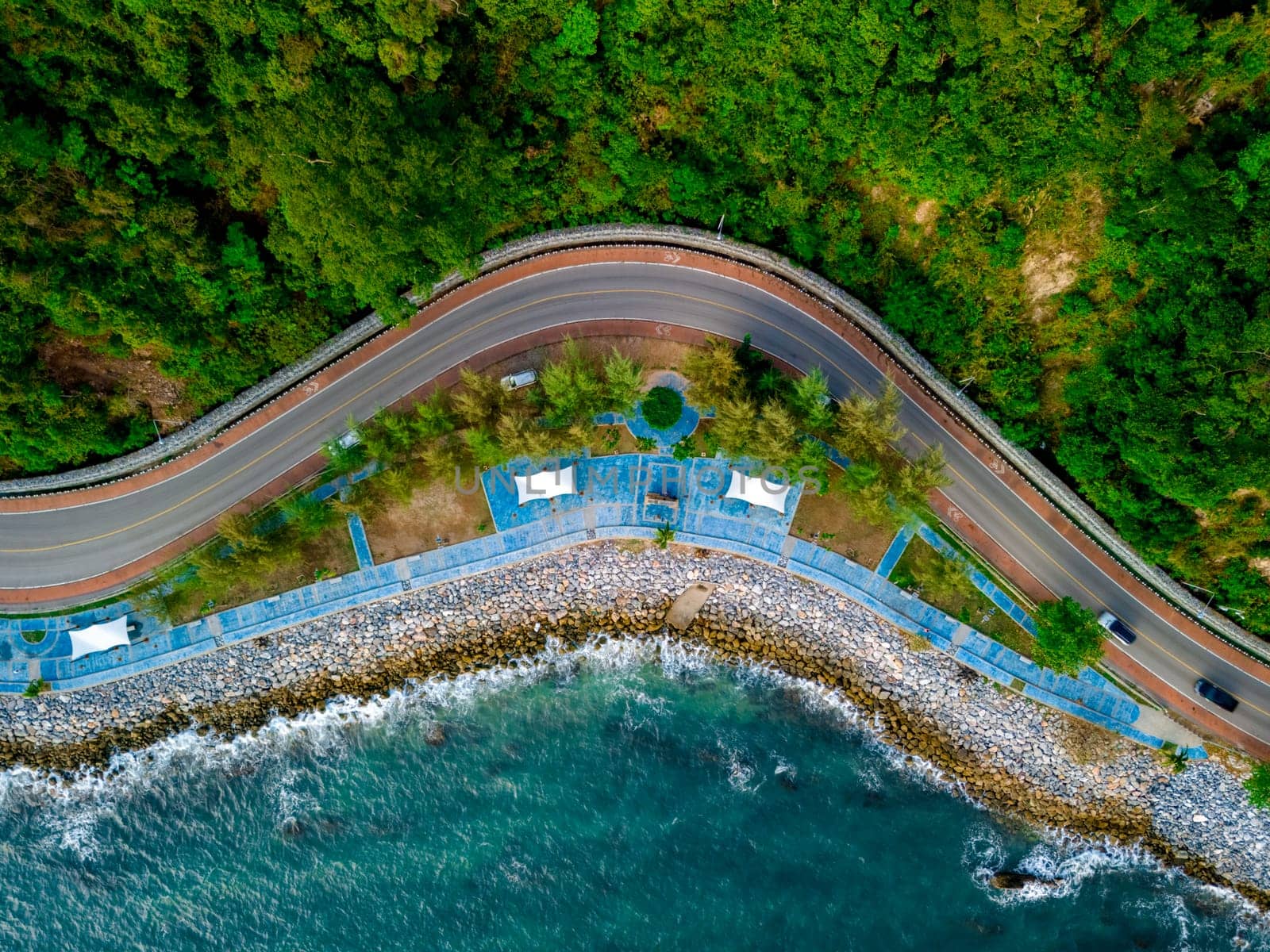 car driving on the curved road alongside the ocean beach road of Thailand. road landscape in summer. it's nice to drive on the beachside highway. Chantaburi Province Thailand, top drone view