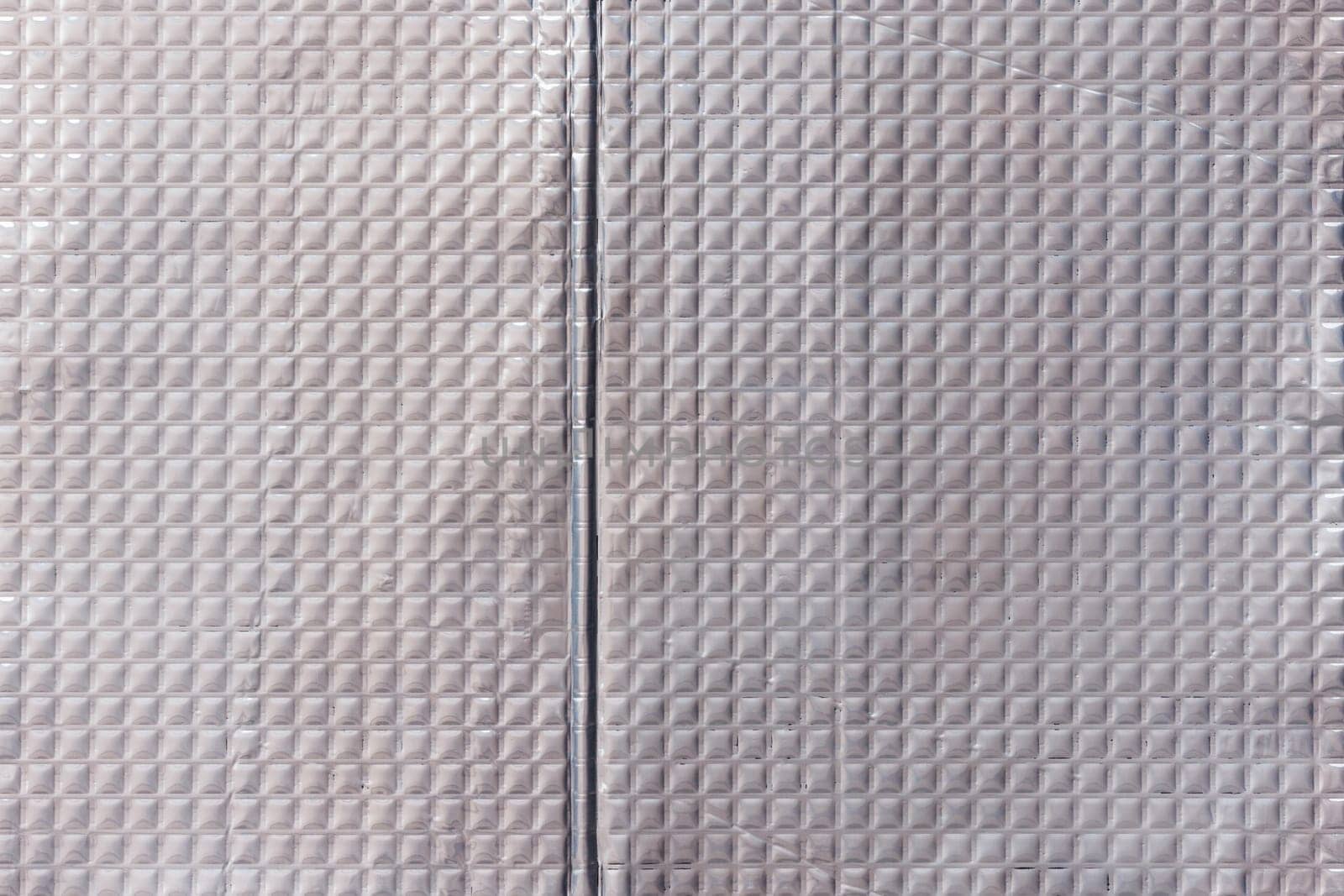 Full-frame texture of aluminum coated butil rubber sheet with square pattern. This material is used for sound dampening in car interiors and vibration resonance reducing and acoustic improving.