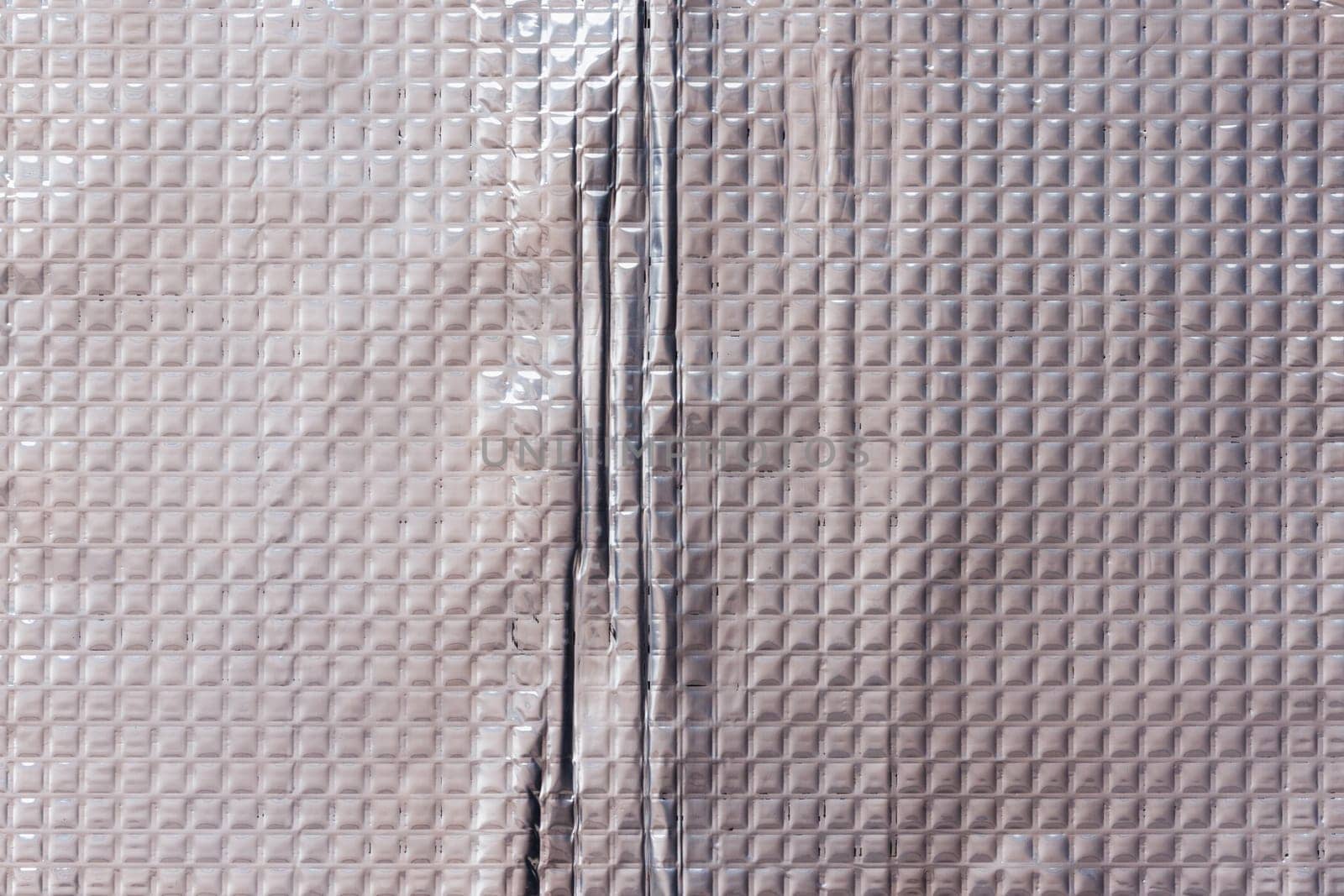 Full-frame texture of aluminum coated butil rubber sheet with square pattern. This material is used for sound dampening in car interiors and vibration resonance reducing and acoustic improving.