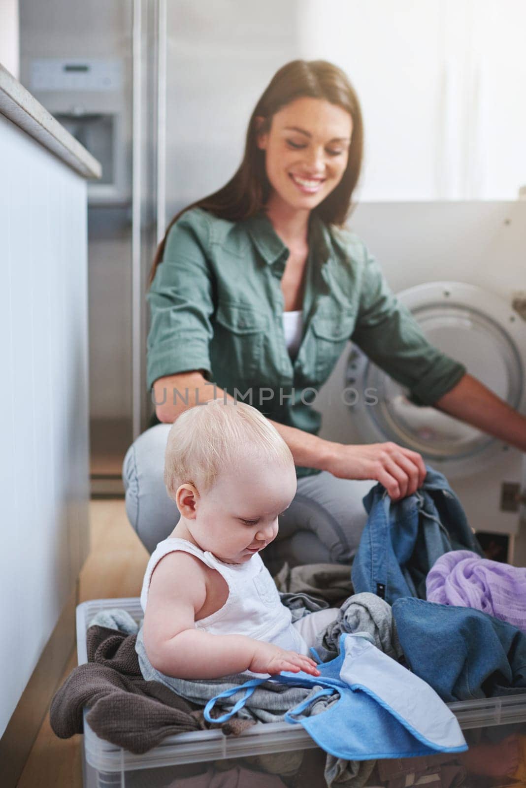 Laundry, washing and mother with baby in home for multitasking, housekeeping and housework. Family, parenting and mom with newborn in clothing basket for cleaning, hygiene and maintenance on floor by YuriArcurs