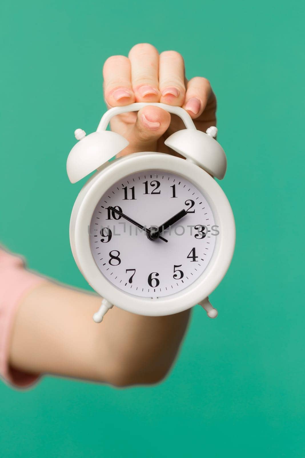 Woman holding alarm clock in hand on blue background isolation - image