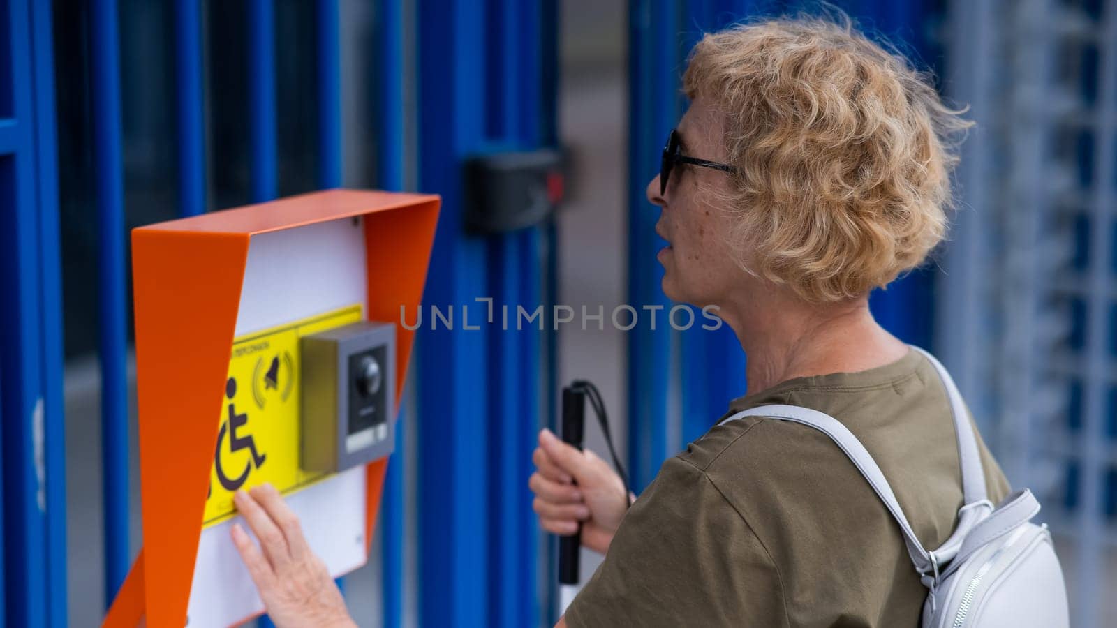 An elderly blind woman reading a text in braille. Button for calling help for people with disabilities. by mrwed54