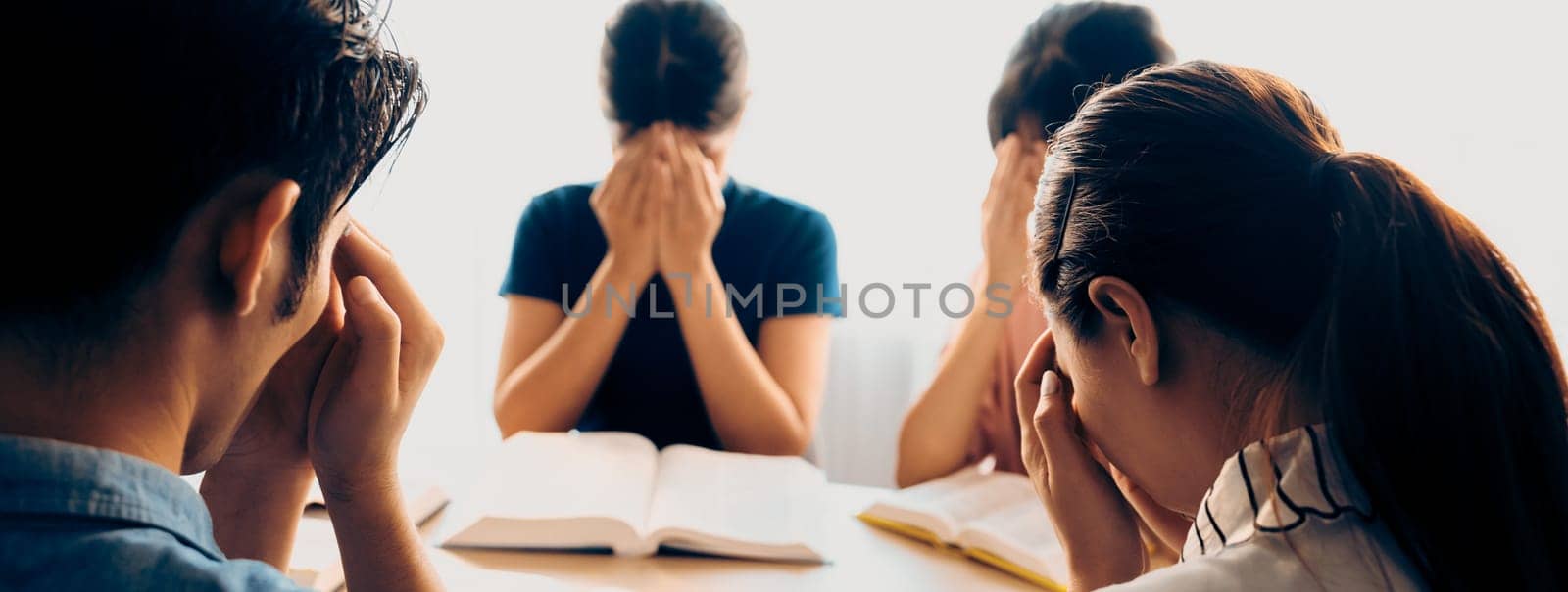 Cropped image of Group of believer hand praying together while raising hand at wooden church on bible book. Prayers hold hand together faithfully. Concept of hope, religion, faith, god blessing. Burgeoning.