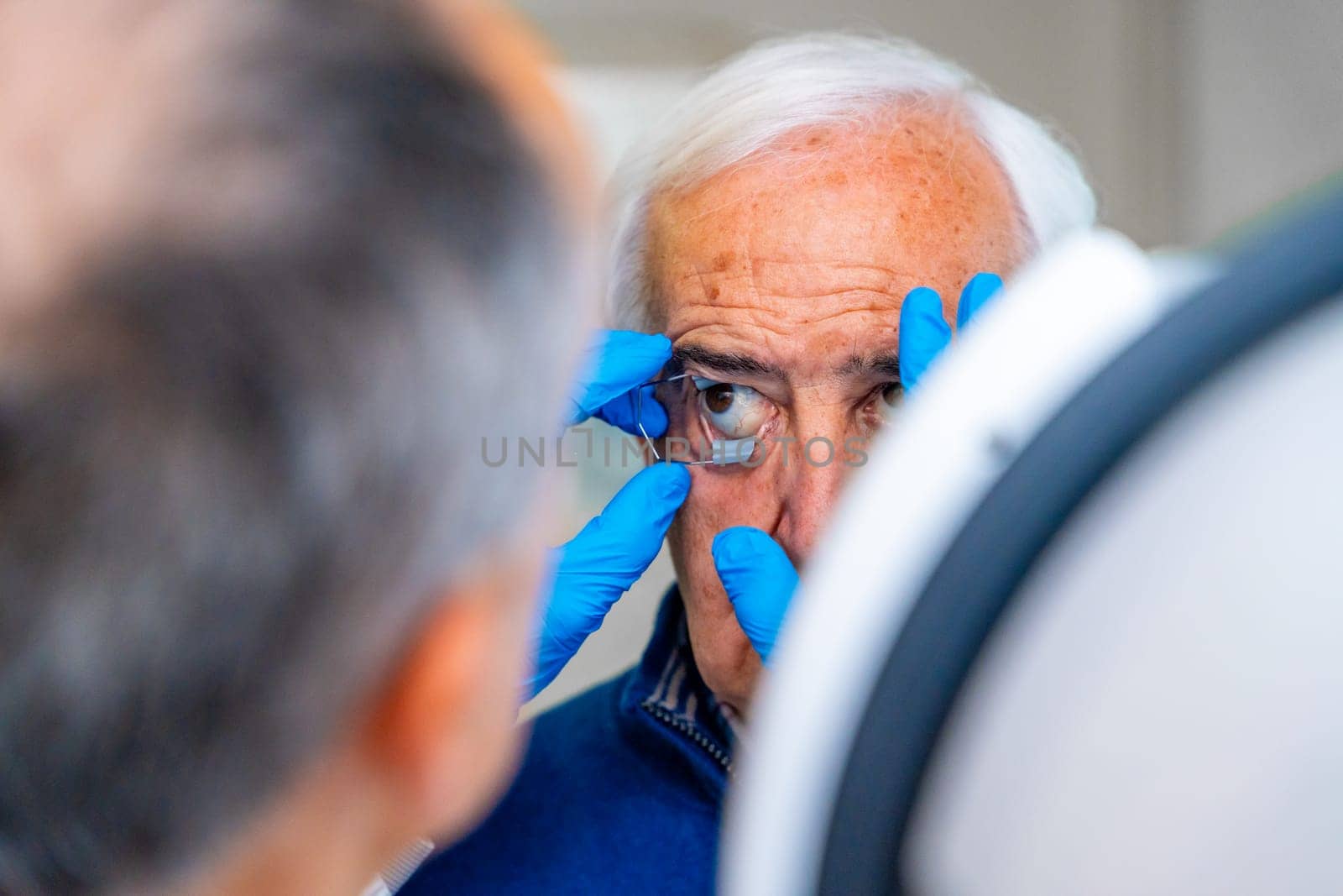 Ophthalmologist placing an eye opener to a senior man by Huizi