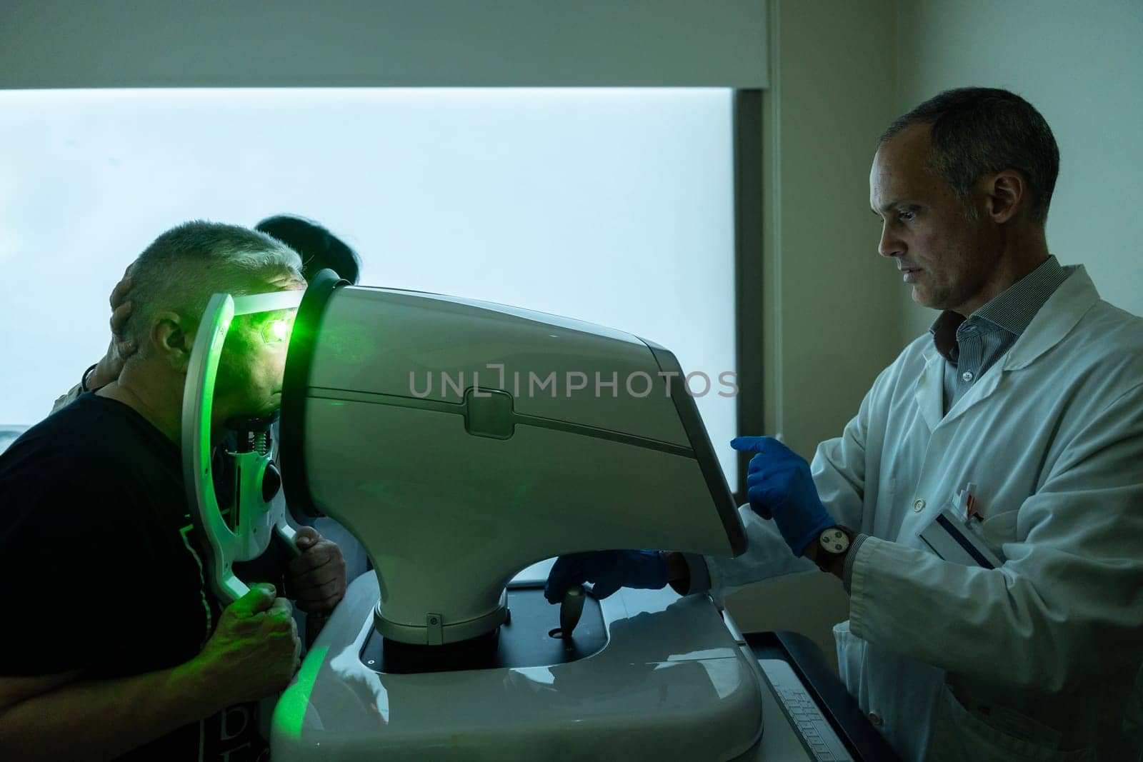 Ophthalmologist treating glaucoma on a senior man using laser machine by Huizi