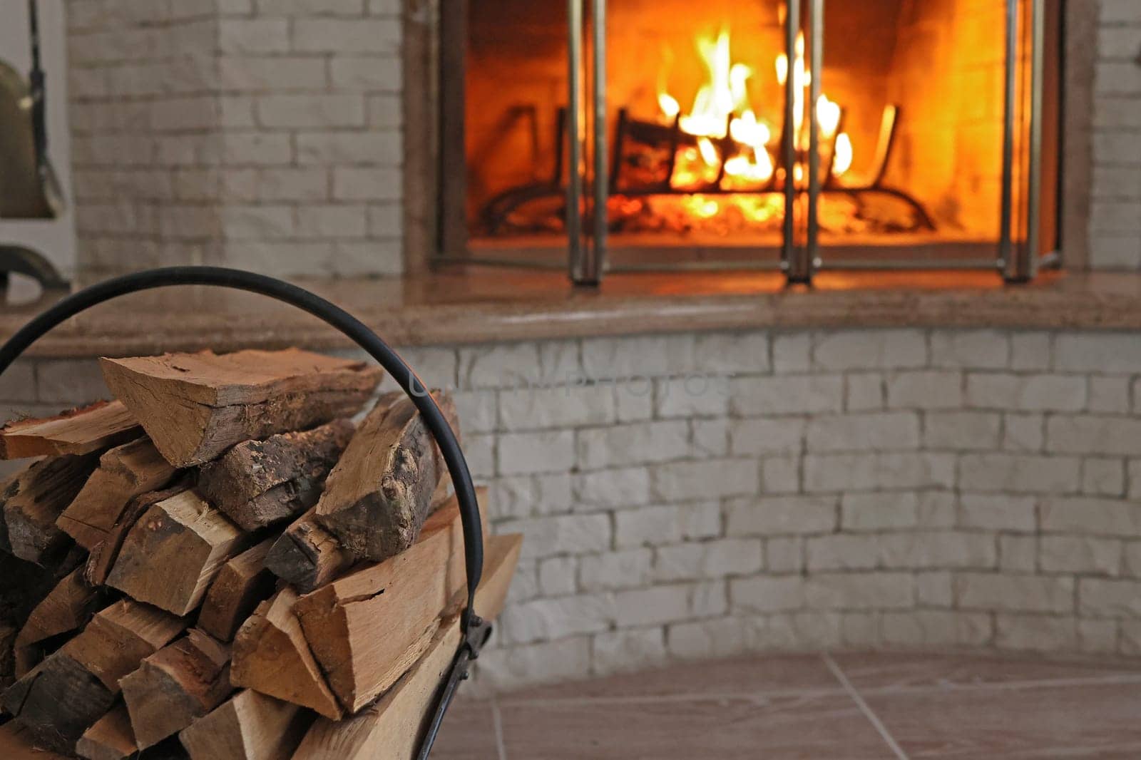 heating the house with wood using a fireplace. firewood is stacked in front of a burning fireplace.
