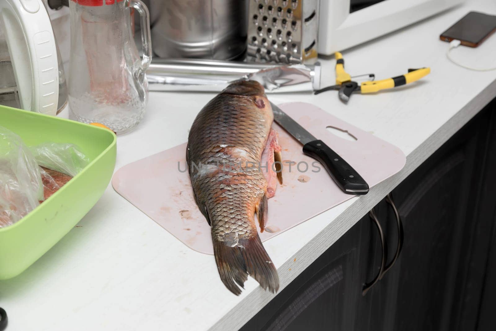 Carp fish and knife on a kitchen table by Nobilior