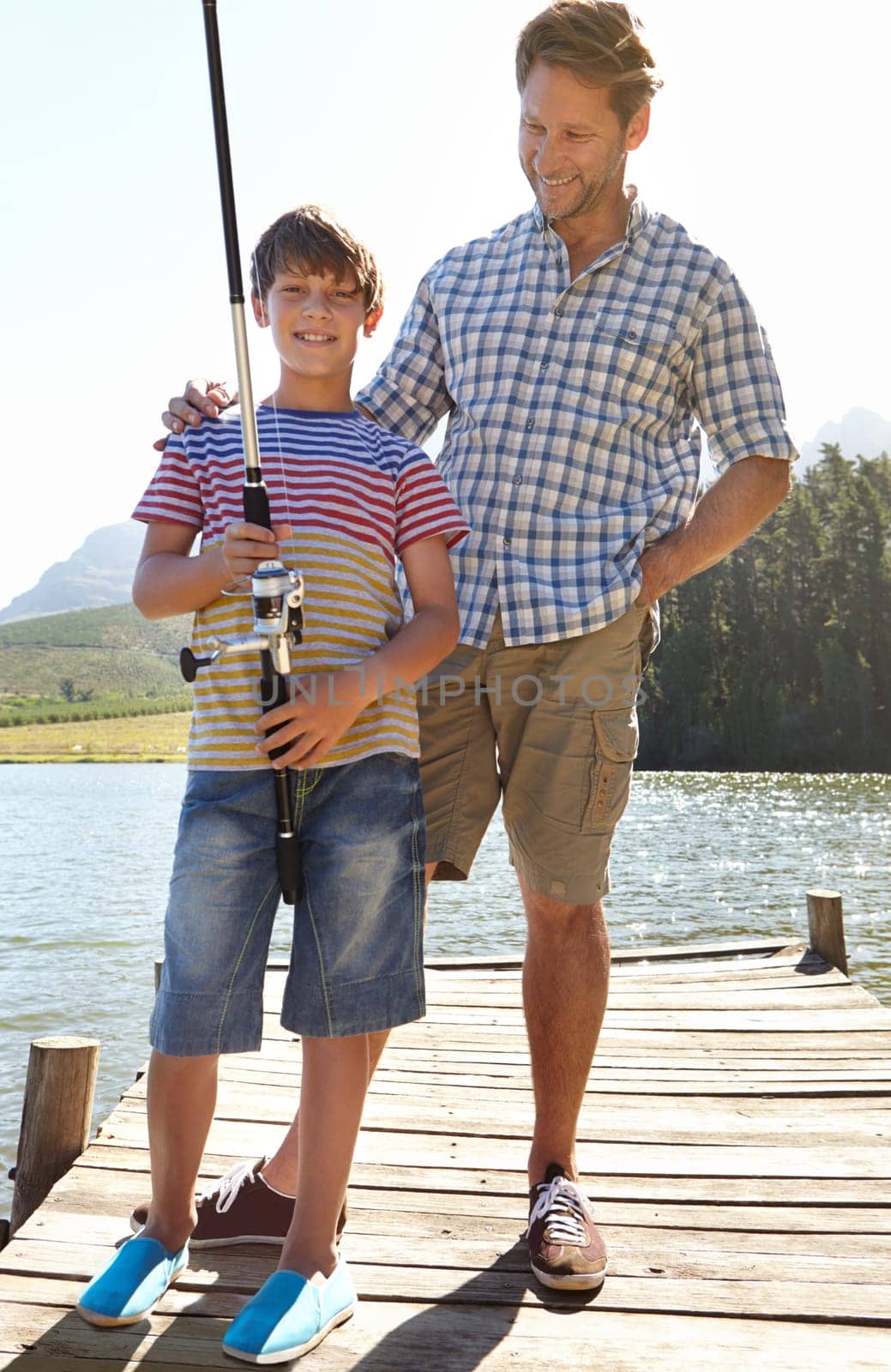 Fishing, lake or pole by father and son in nature bonding, vacation or travel adventure outdoor. Family, love and kid with dad at a river for learning, teaching or sustainable living while camping by YuriArcurs