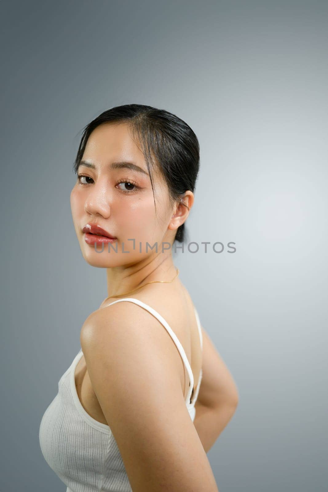 Attractive young woman posing and looking at camera on white at the photo studio.