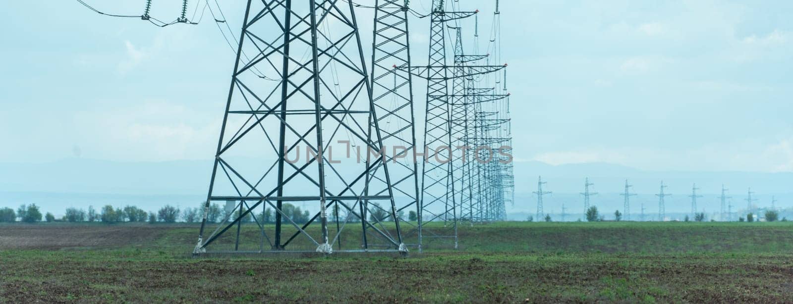 High voltage towers with sky background. Power line support with wires for electricity transmission. High voltage grid tower with wire cable at distribution station. Energy industry, energy saving.