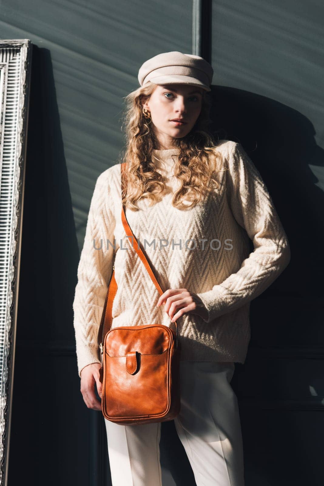 Studio portrait of beautiful woman with a curly blond hair holding brown bag, posing on gray background. by Ashtray25