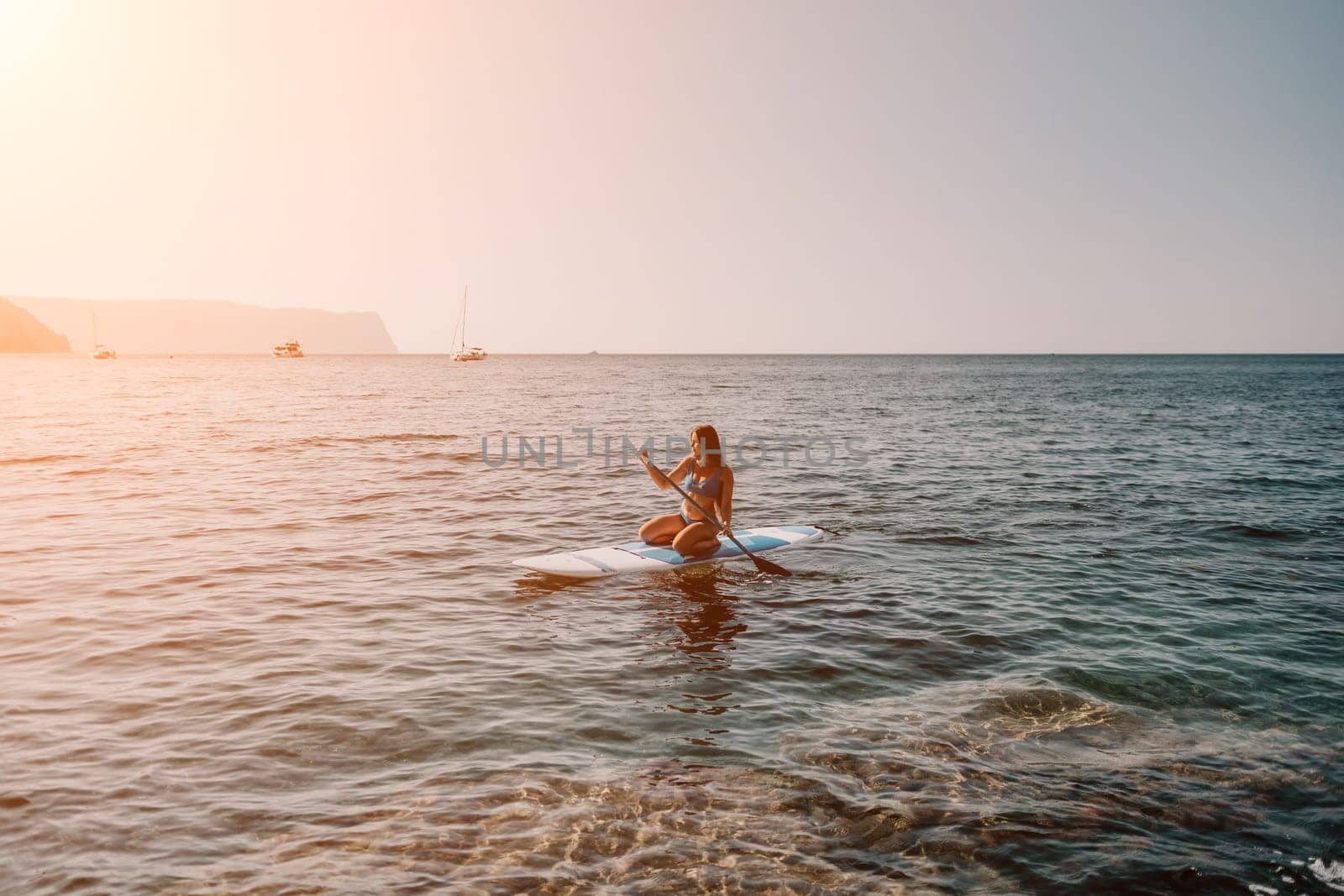 Close up shot of happy young caucasian woman looking at camera and smiling. Cute woman portrait in bikini posing on a volcanic rock high above the sea