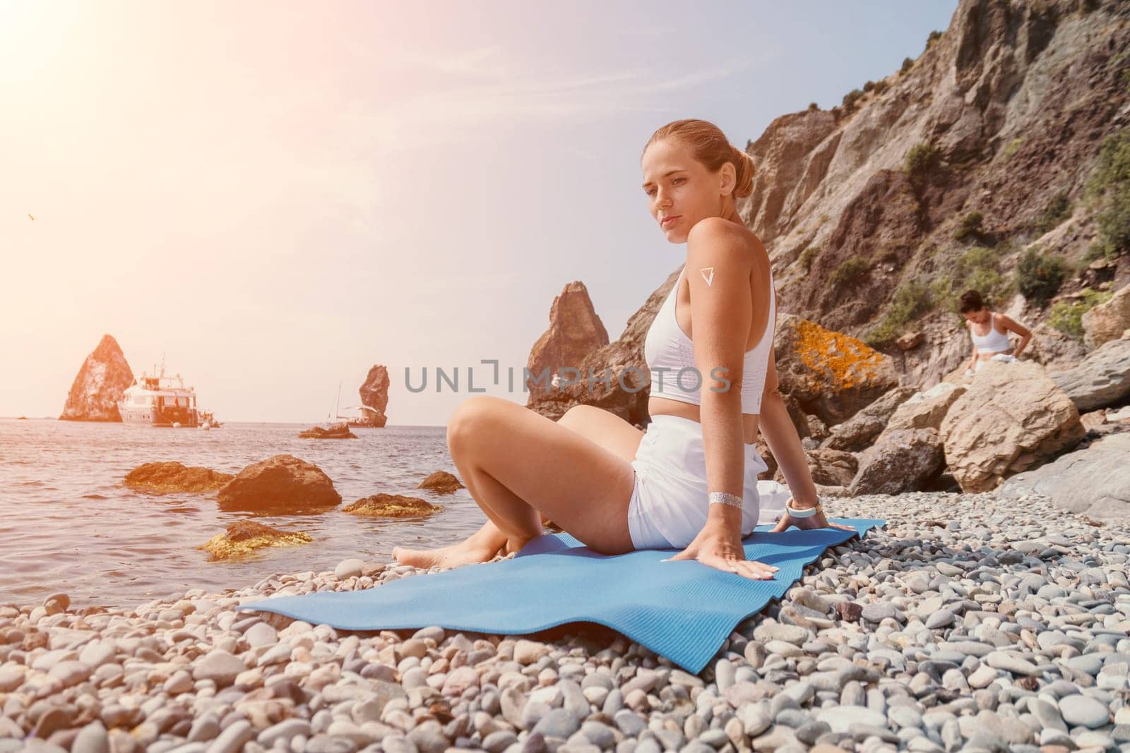 Woman sea yoga. Happy women meditating in yoga pose on the beach, ocean and rock mountains. Motivation and inspirational fit and exercising. Healthy lifestyle outdoors in nature, fitness concept. by panophotograph