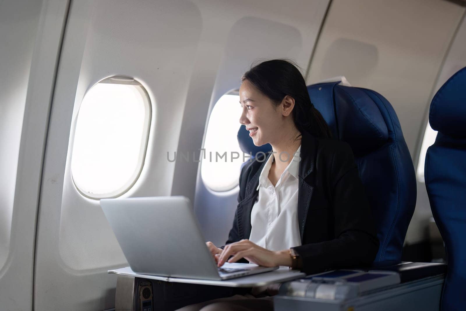 Asian young woman using laptop at first class on airplane during flight, Traveling and Business concept by nateemee