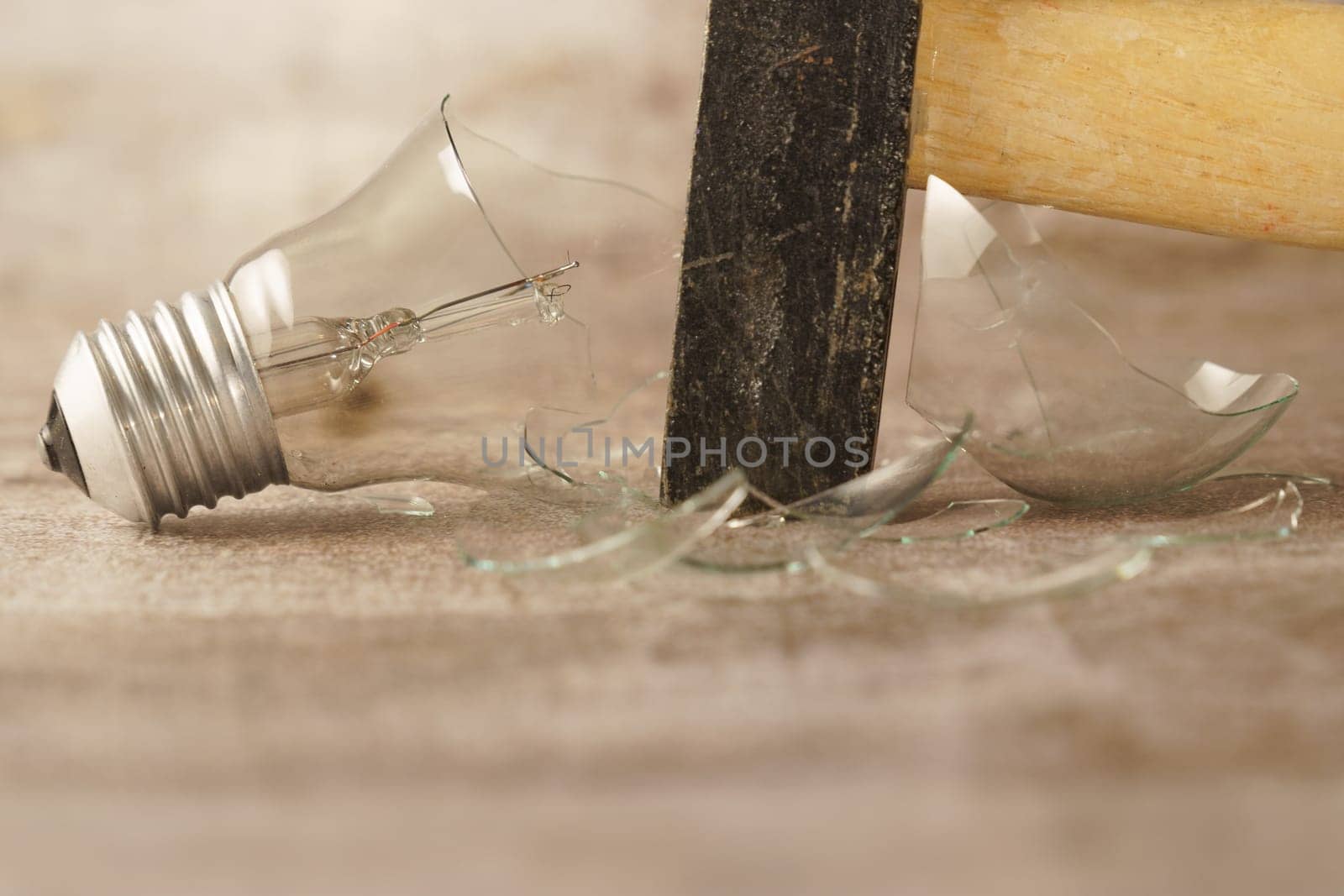 closeup of a hammer breaking a light bulb