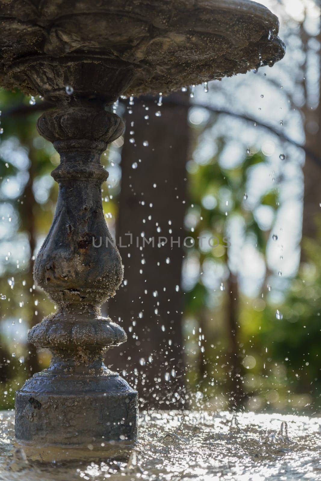 water from a public fountain splashing in the sunlight by joseantona